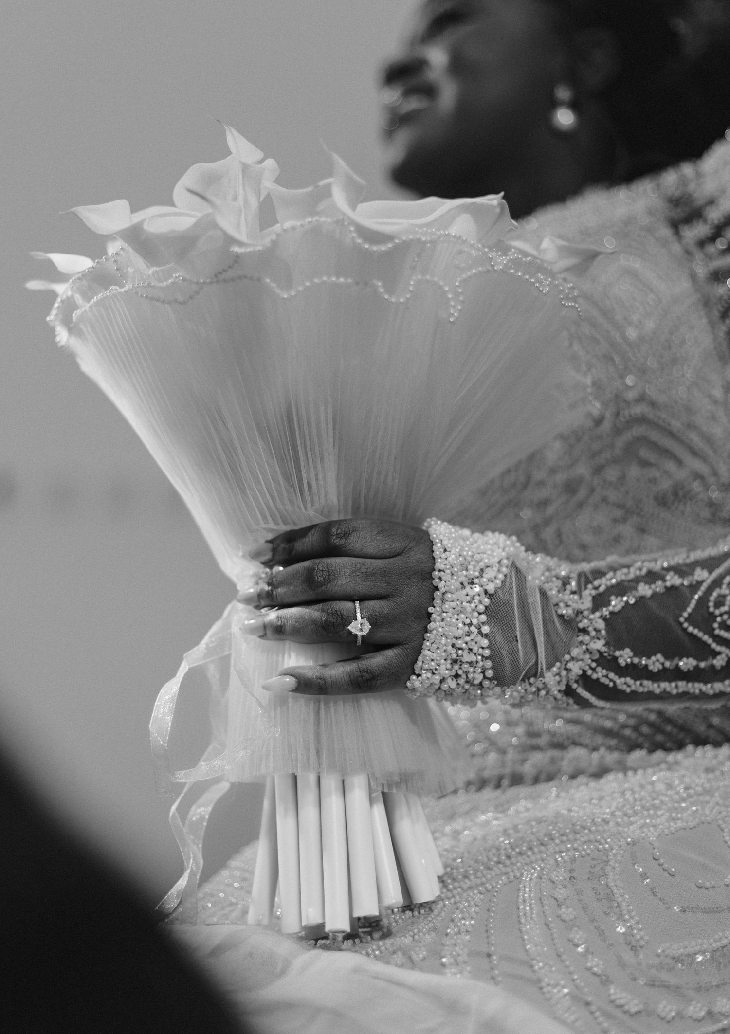 Close-up of delicate pleated fabric and ring detail in black and white.