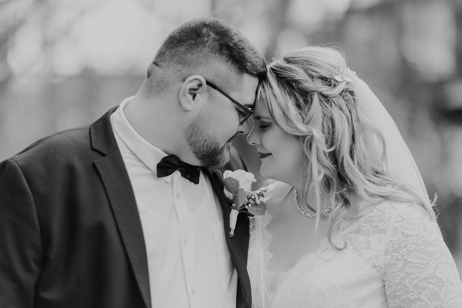 Ein zartes Schwarz-Weiß-Hochzeitsporträt, das einen intimen Moment zwischen Jungvermählten zeigt.