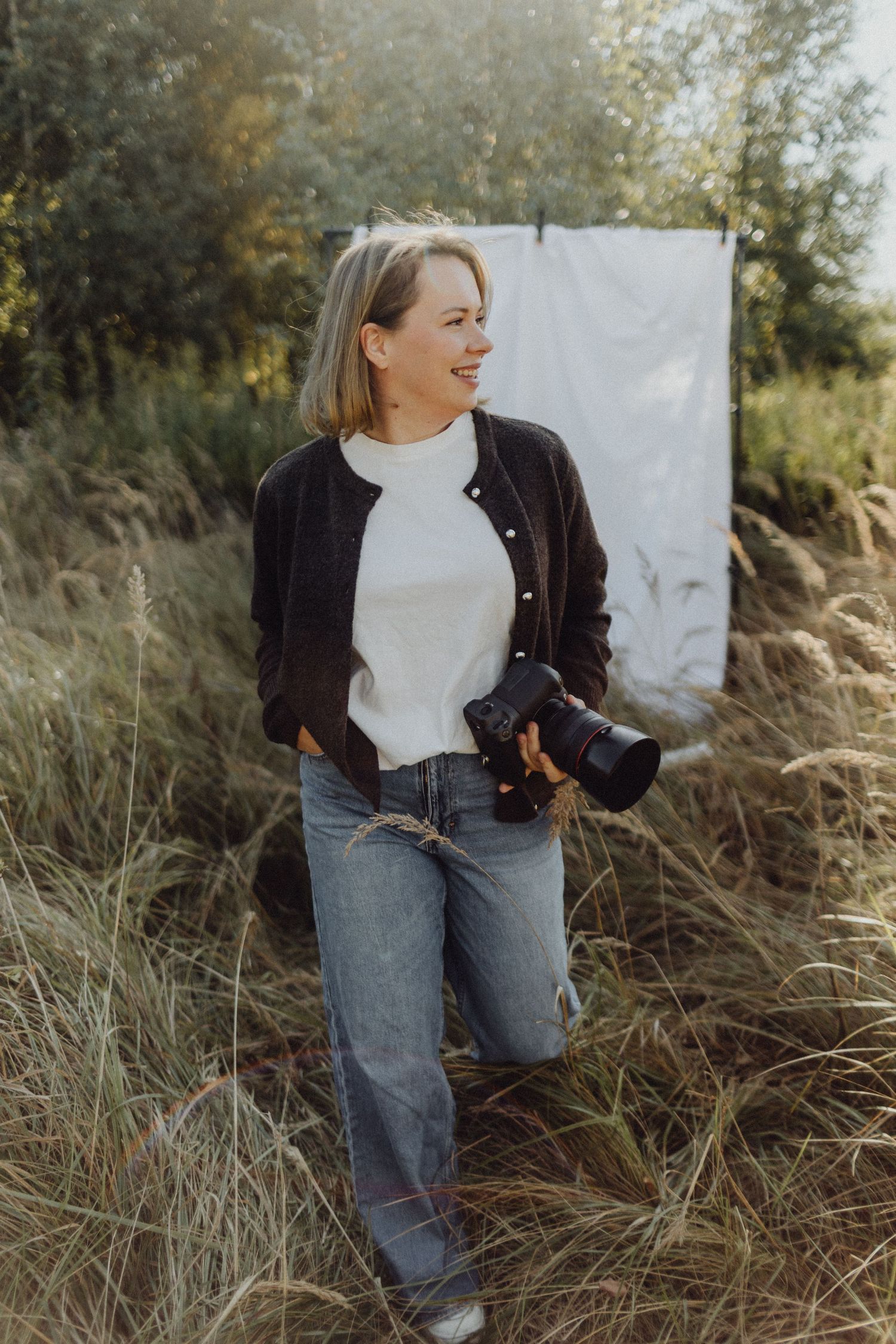Person in white turtleneck and brown jacket poses against autumn grass in outdoor portrait series.
