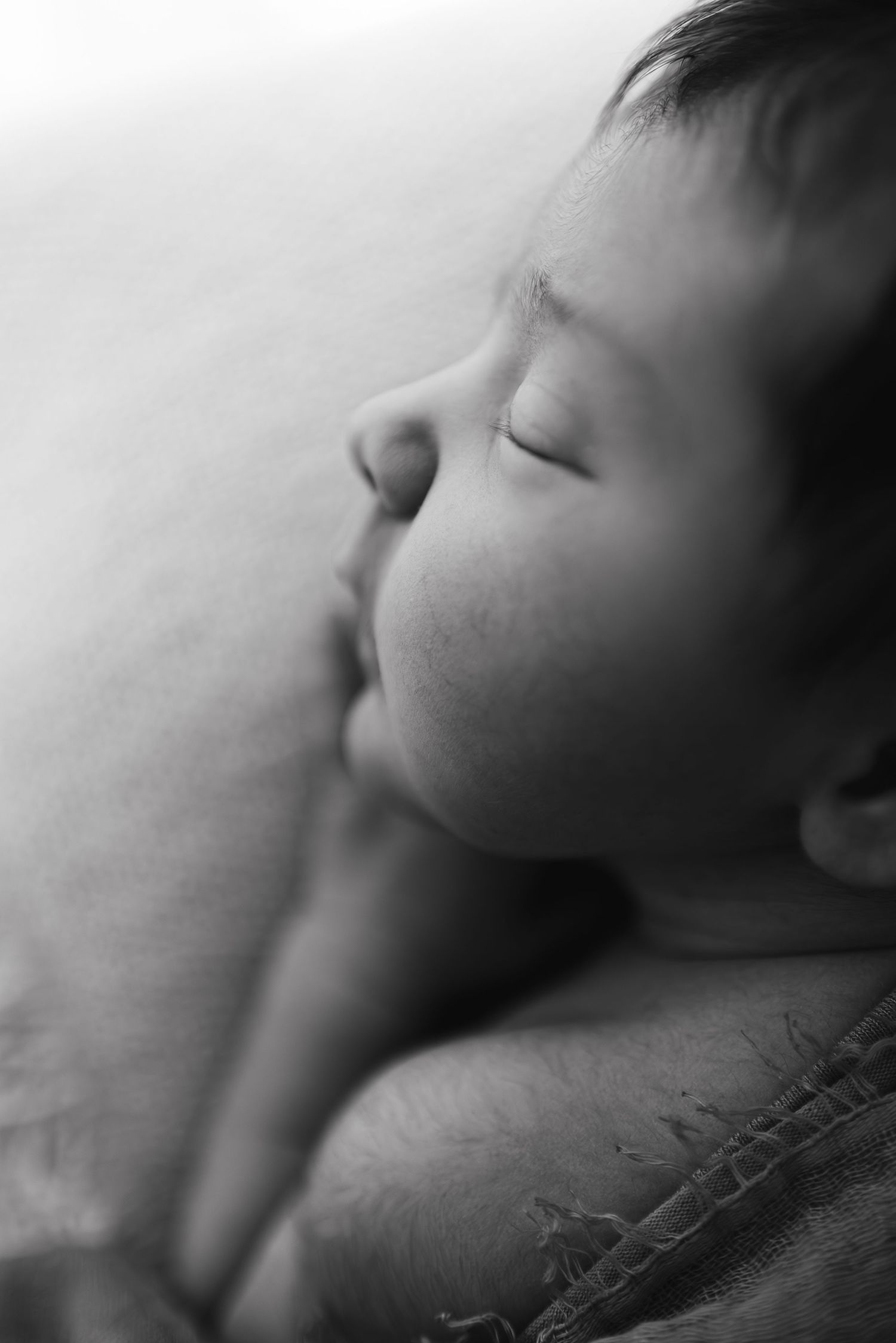 Peaceful sleeping newborn baby in black and white portrait with soft focus background.