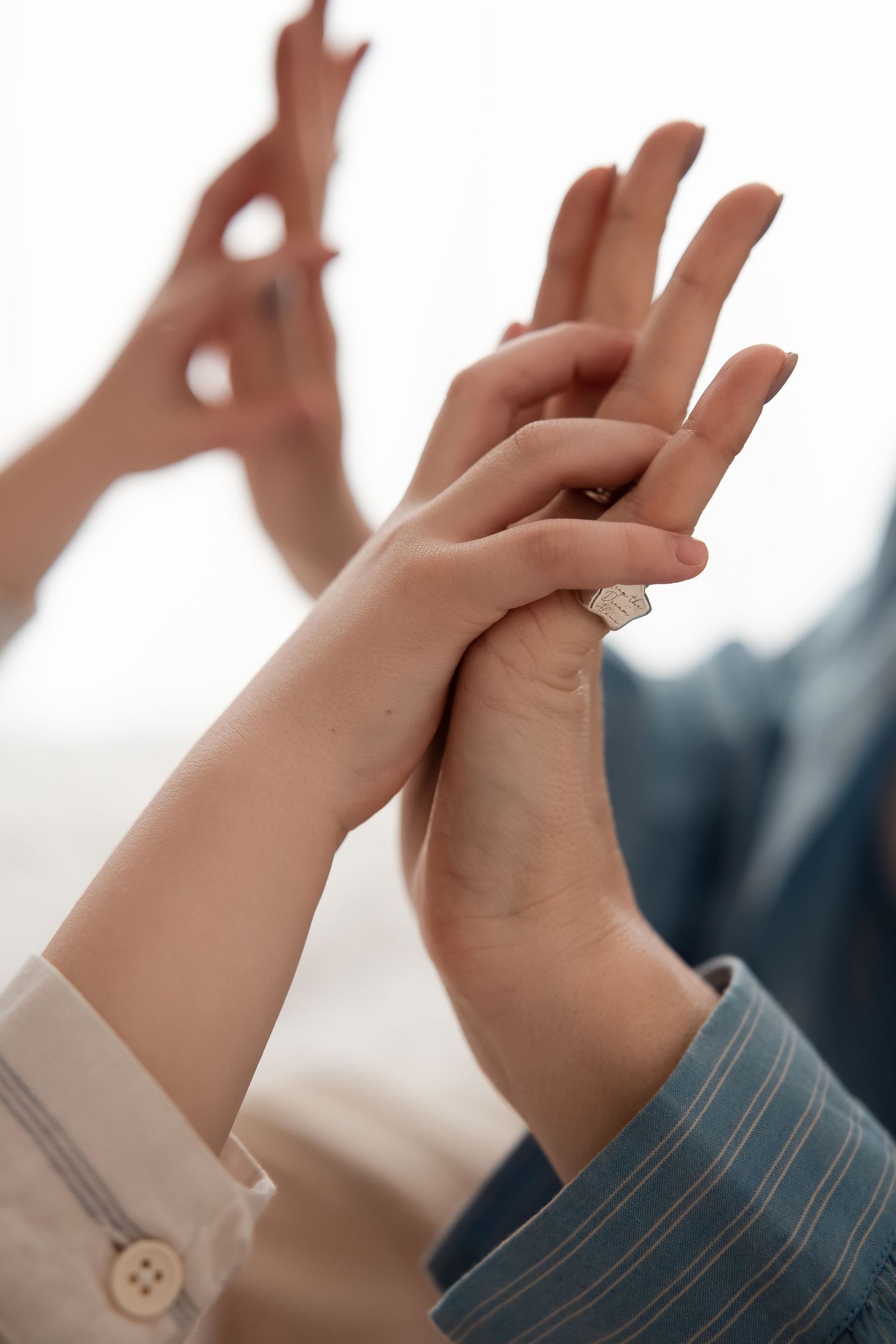 Close-up of two people holding hands with diamond engagement ring visible on finger.