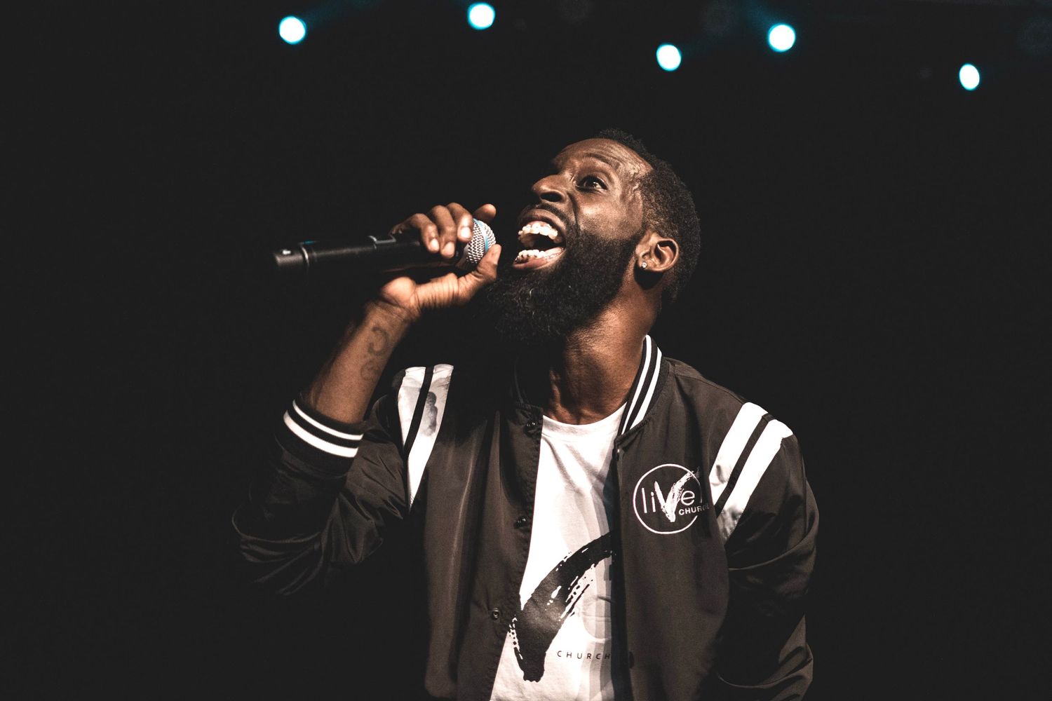 Singer performing passionately on stage with dramatic lighting effects.