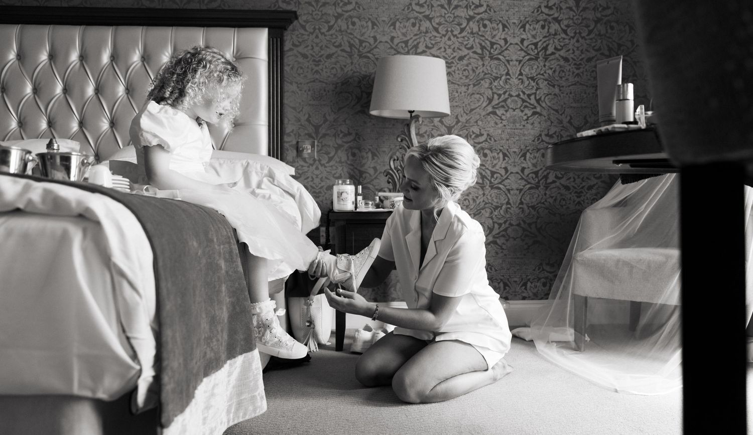 Bridesmaid helps flower girl put on shoes before wedding at Clanard court wedding venue