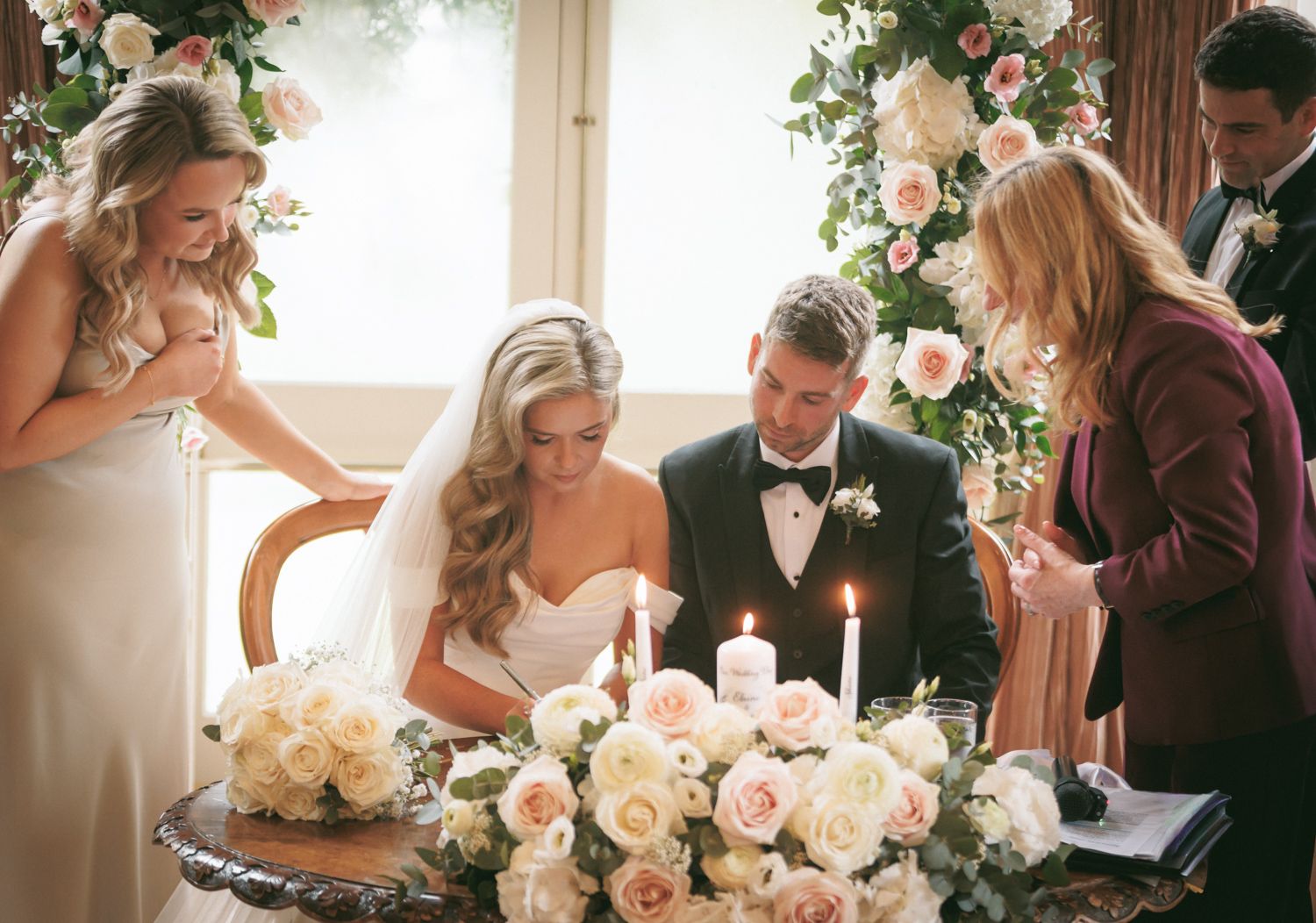 Happy couple signing the wedding register with loved ones watching and celebrating the moment at Tinakilly country house Ireland