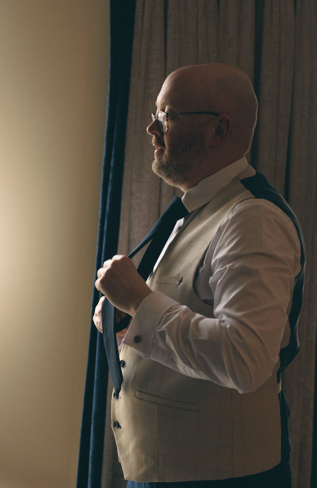 Groom putting on tie at clanard court wedding venue before ceremony