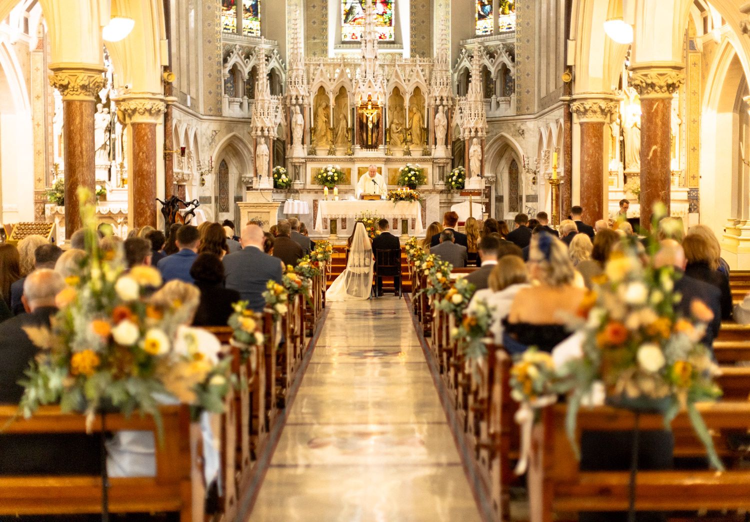 Wide view of a church wedding ceremony with guests by Paul Cowhig