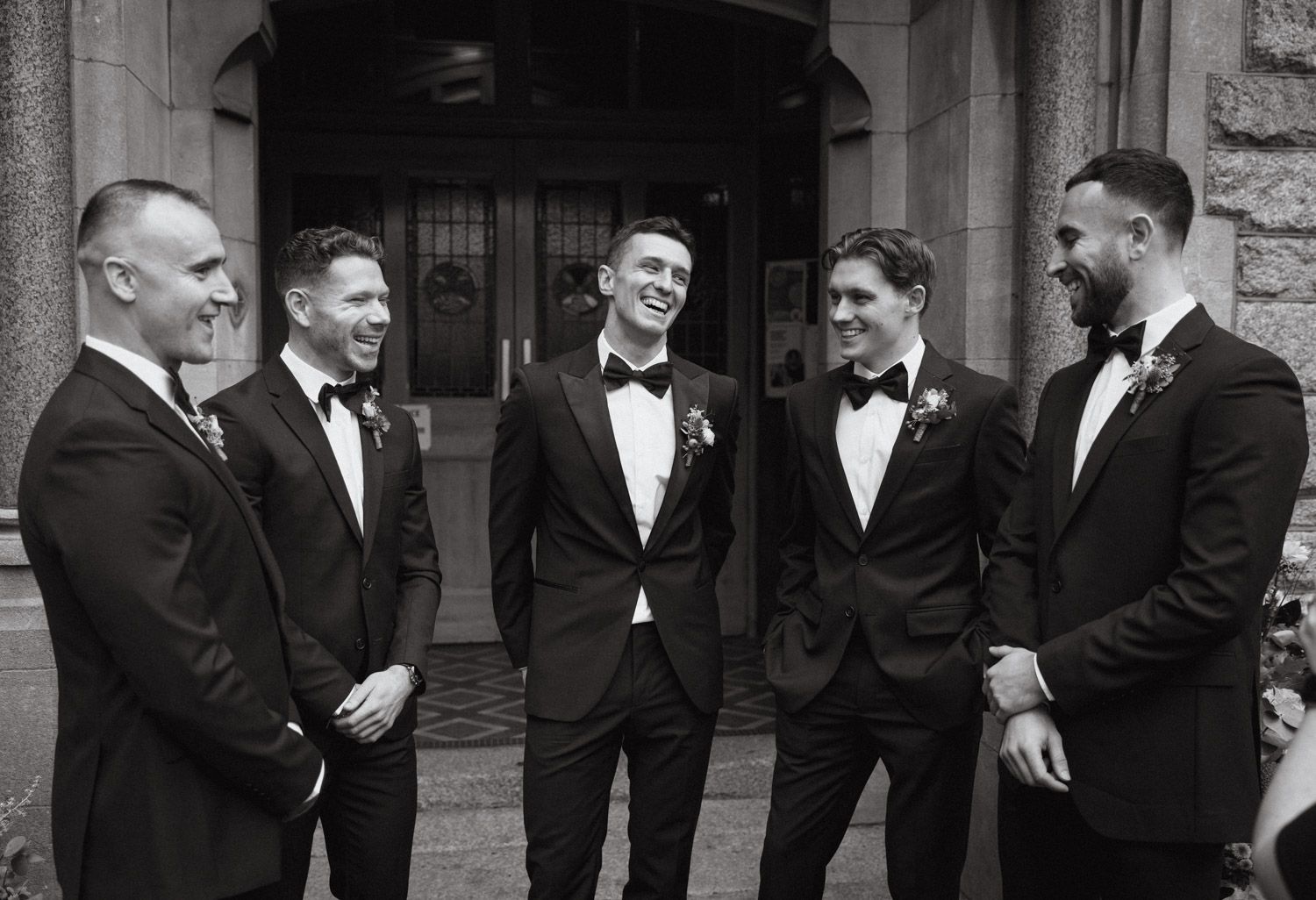 Groom laughing with groomsmen during wedding morning preparations