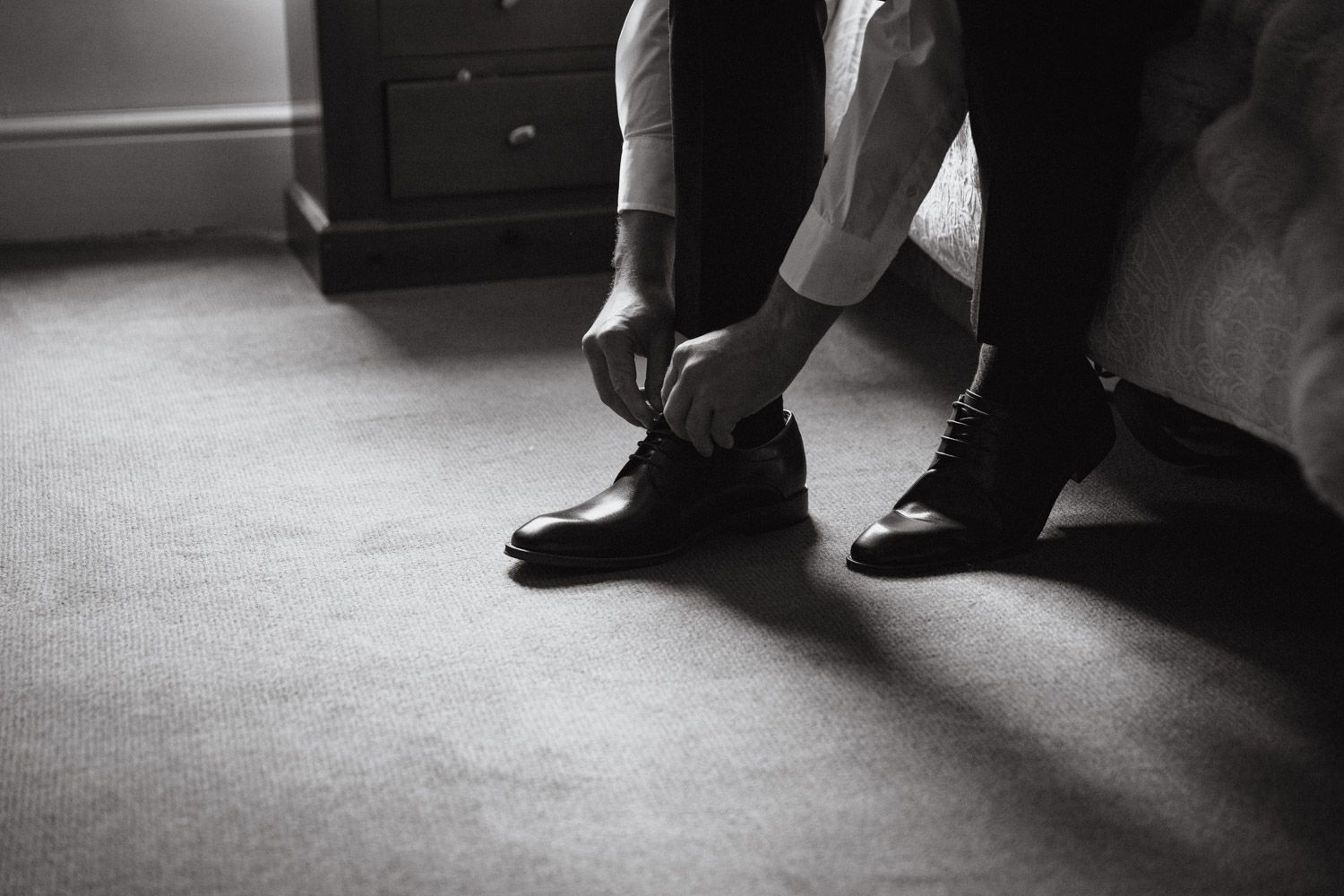 Black and white close up of groom putting on his shoes on the morning of his wedding in Dublin, Ireland