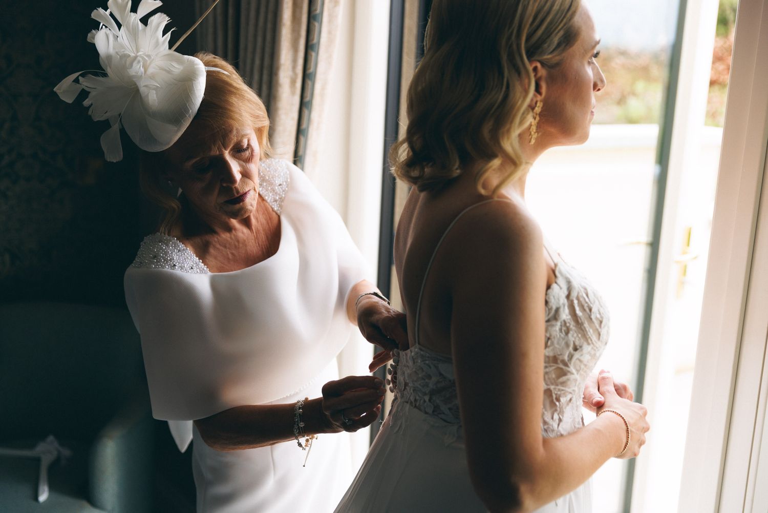 Brides mother helping bride with dress before wedding at Clanard court wedding