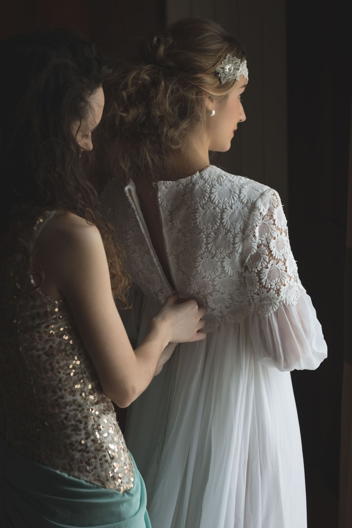 Bridesmaid helping bride with dress before wedding in Cork photographed by Paul Cowhig