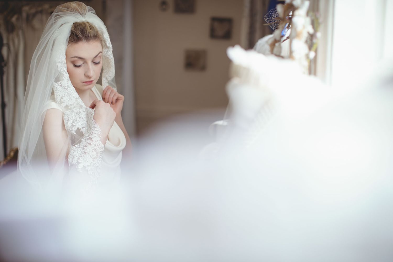 Bride standing at window holding veil before wedding in cork city