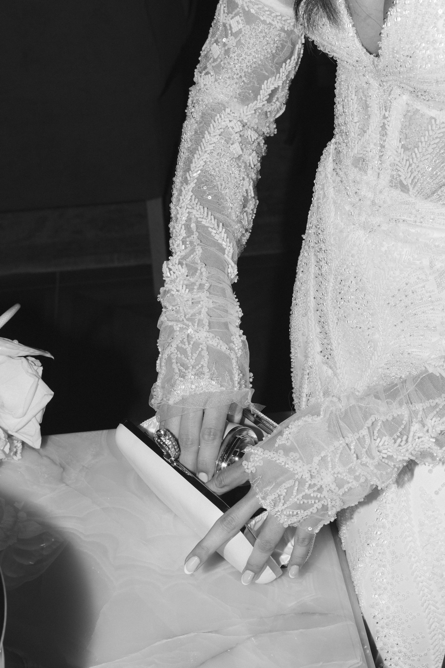 Close-up details of intricate white lace wedding dress with delicate embellishments.
