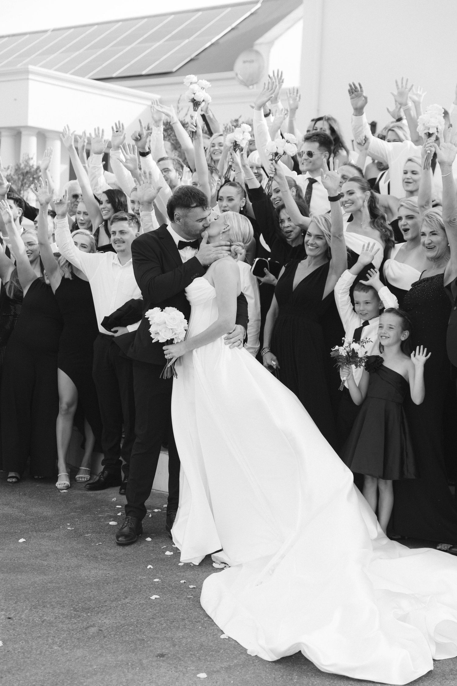 Wedding guests raise their hands in celebration as the bride and groom dance at their reception.