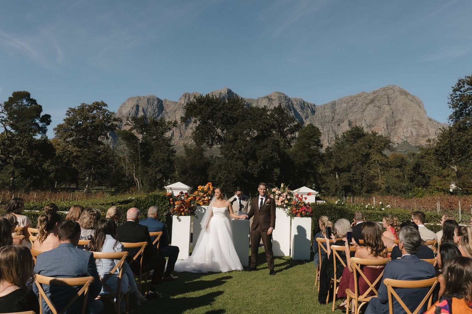 Outdoor wedding ceremony setup with wooden chairs facing mountain vista.