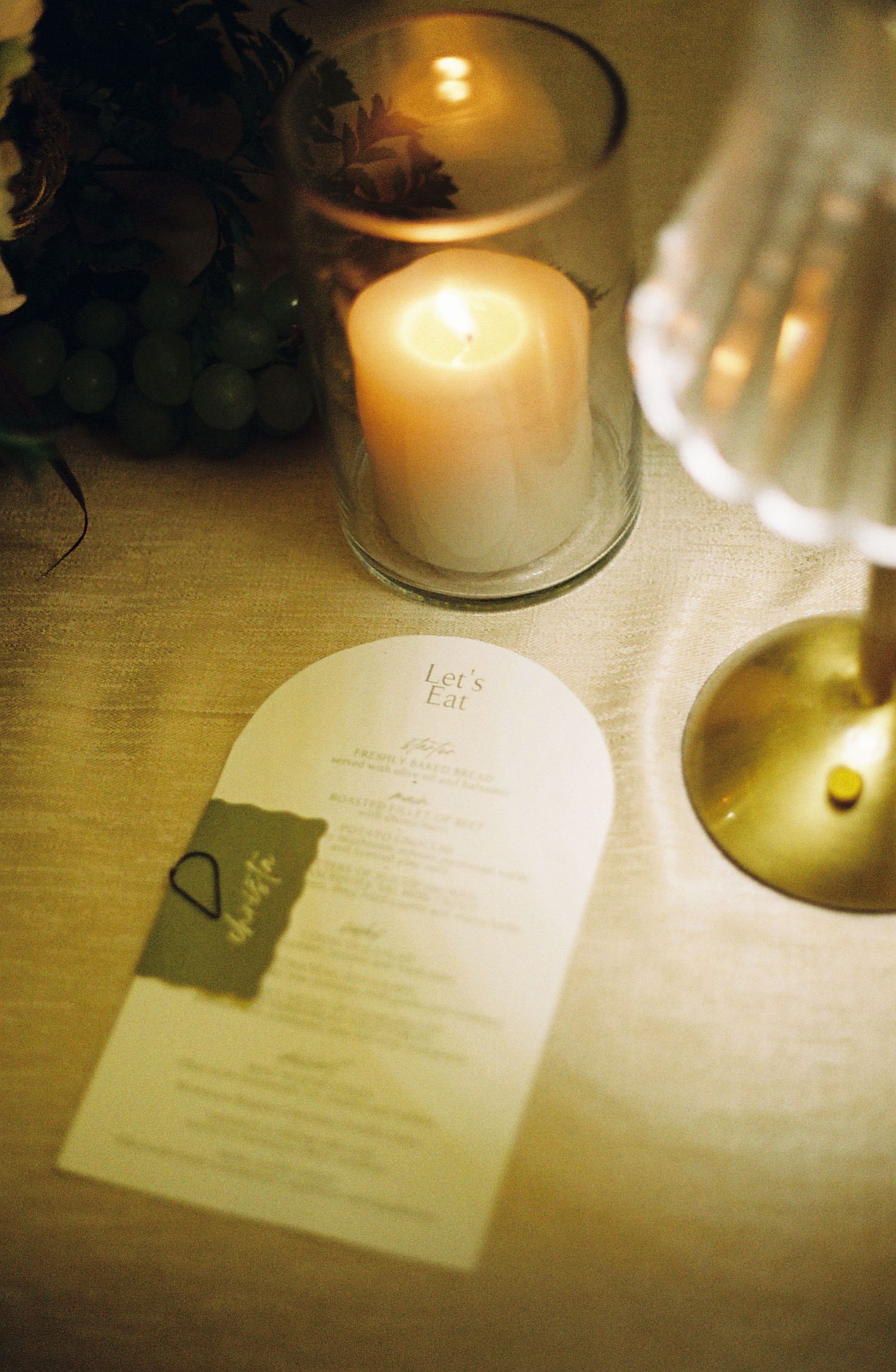Candlelit table setting with menus and glassware creating an intimate dining atmosphere.