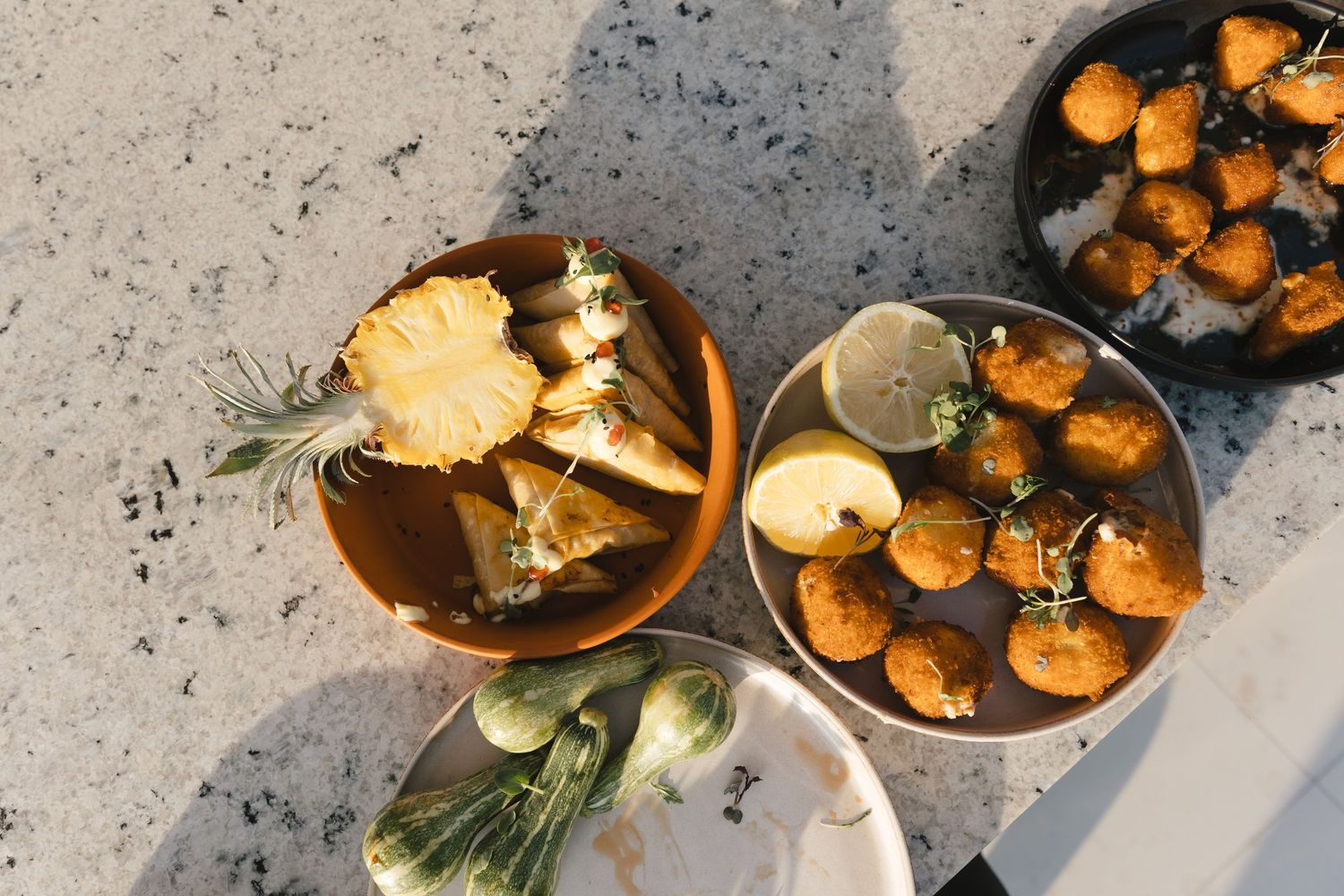 Overhead view of golden brown roasted butternut squash pieces arranged on a dark surface with herbs and seasonings.