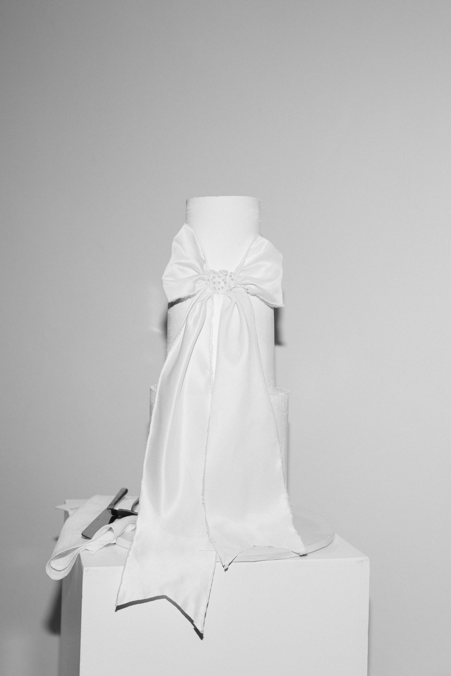 A series of white gift boxes with bows arranged in a minimalist style against a light gray background.