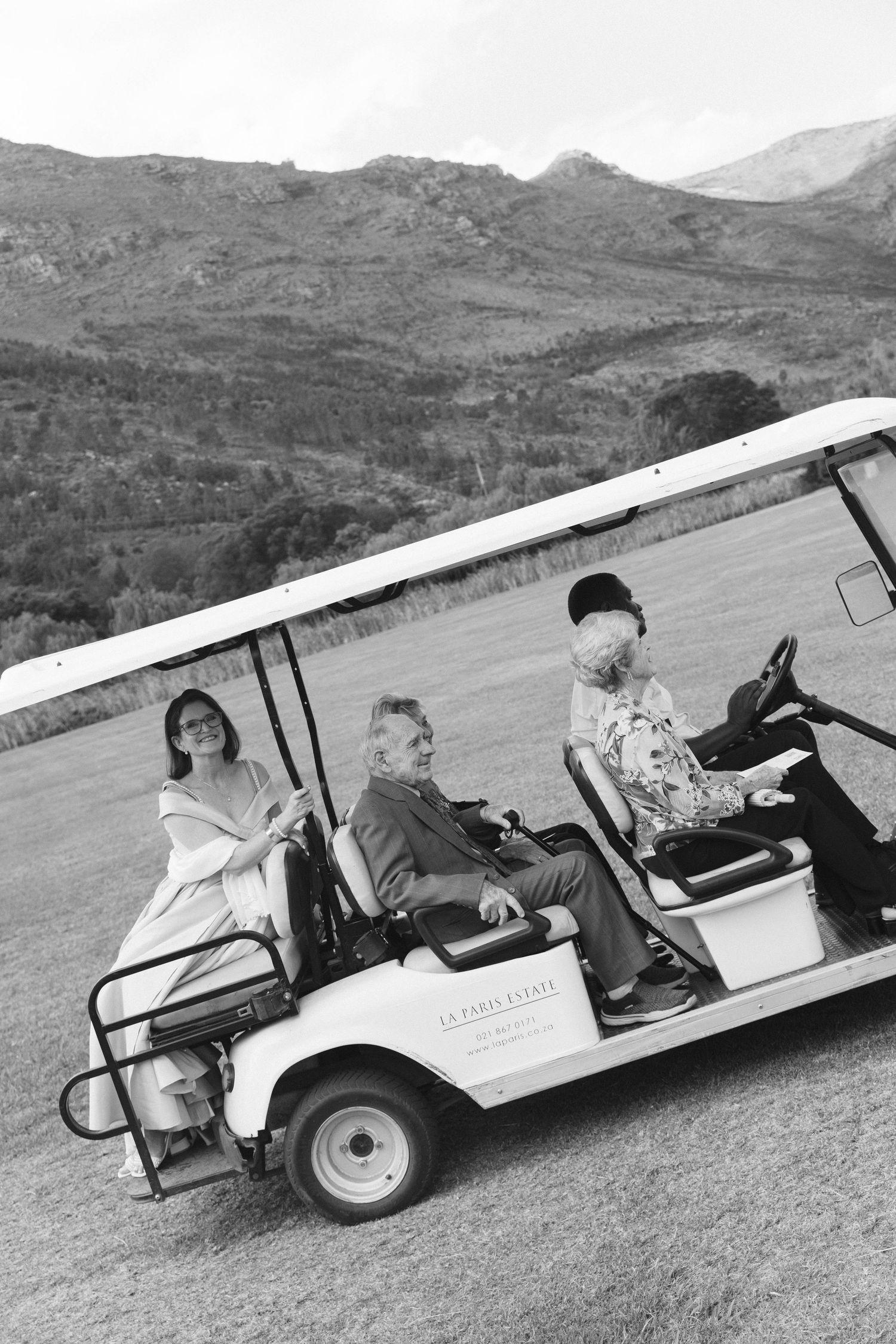 A golf cart rolls sideways down a grassy hill slope at a golf course with mountains in the background.