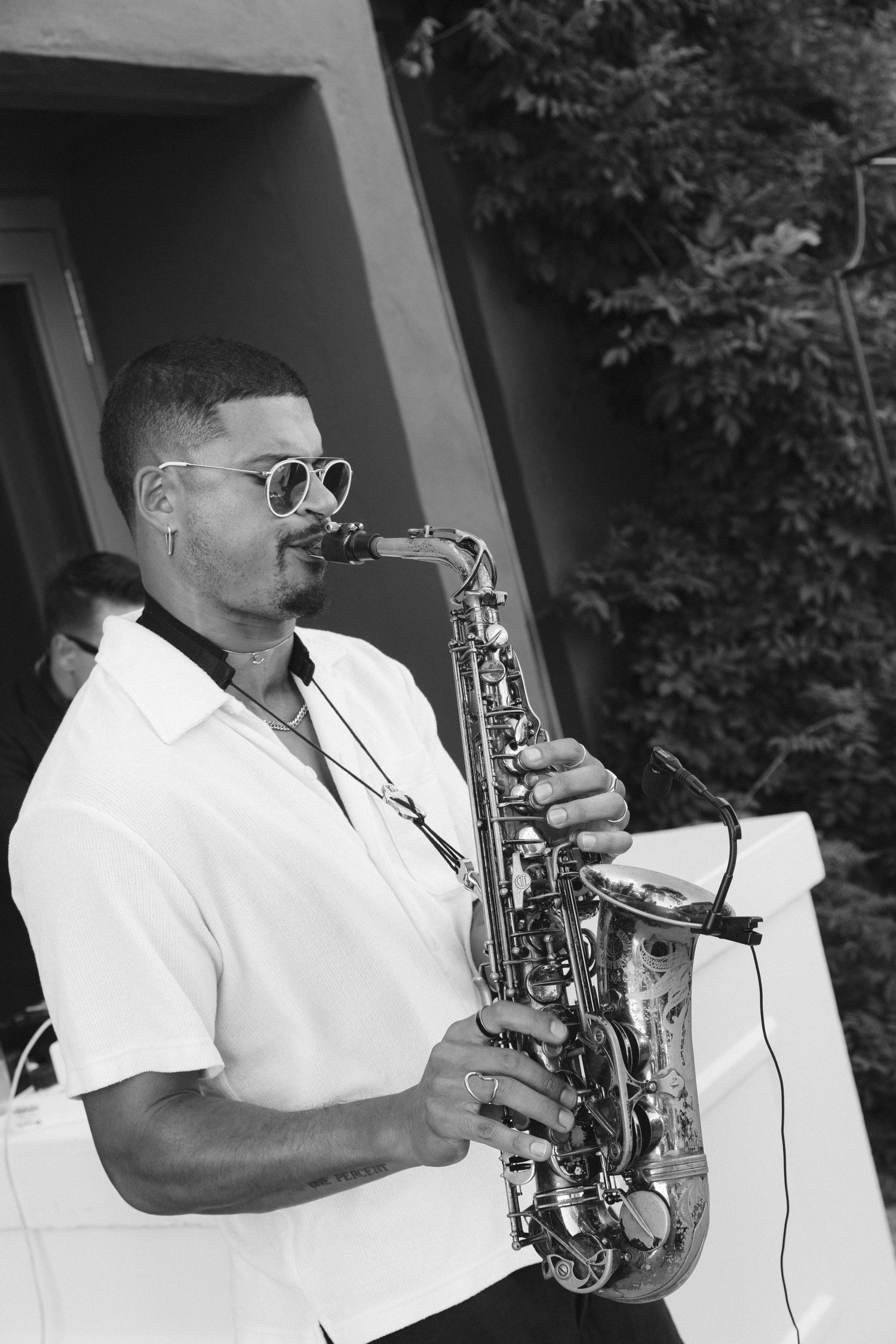 A sequence of black and white photographs showing a saxophone player in white clothing performing on stage.