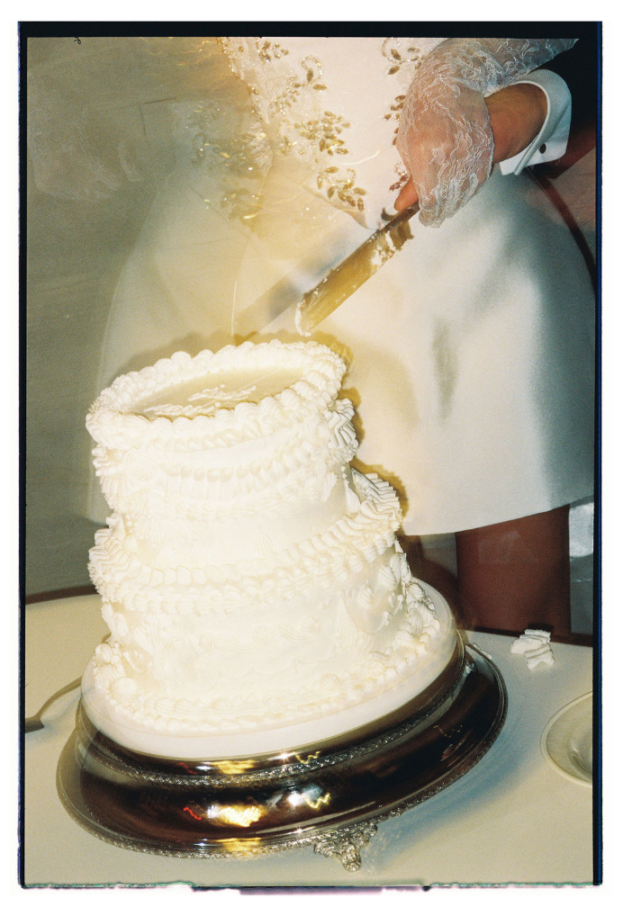 A series of photos showing a white wedding cake being cut into slices on a silver serving platter.