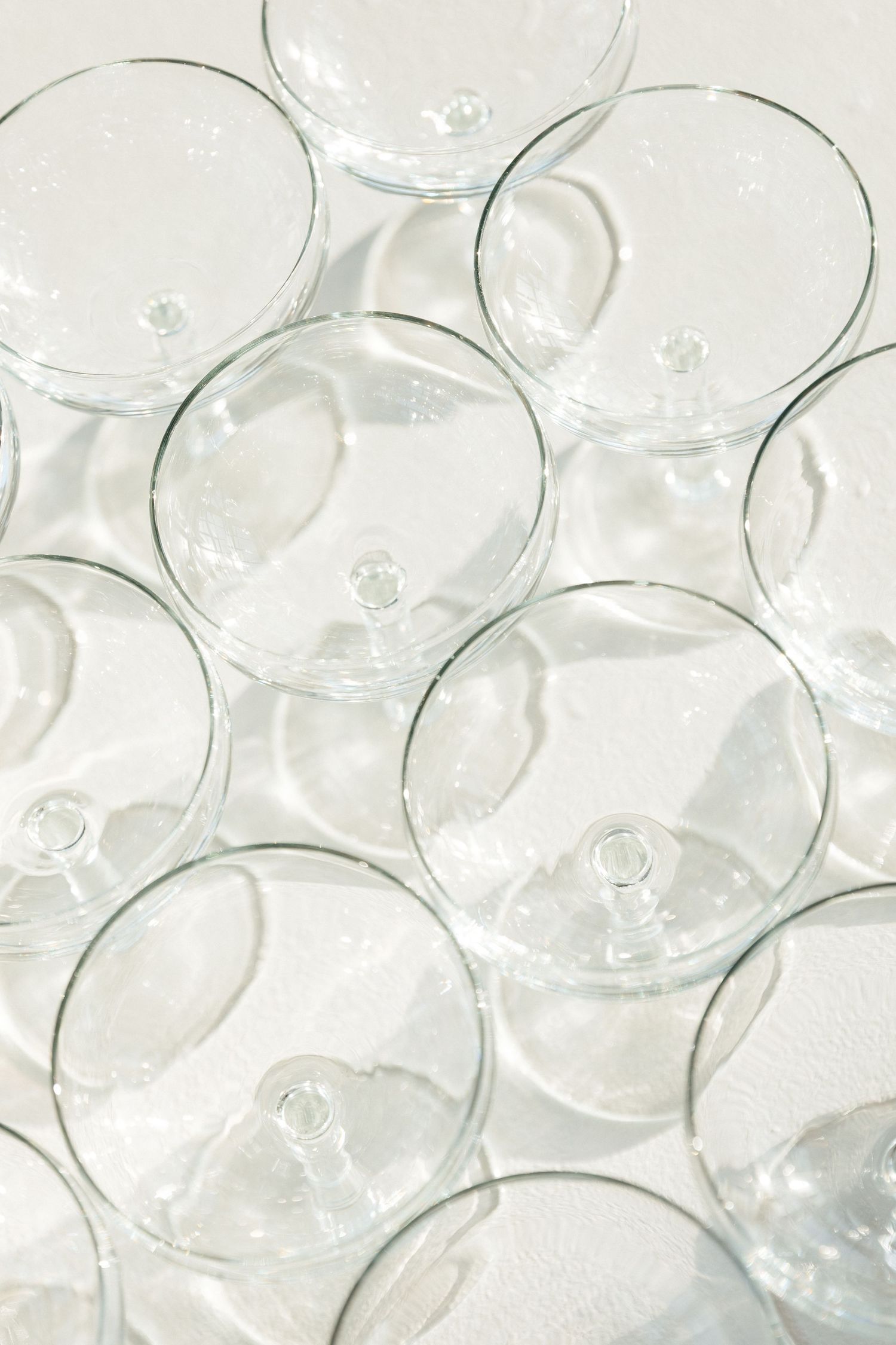Clear glass wine glasses arranged in overlapping circular patterns creating a transparent geometric design.