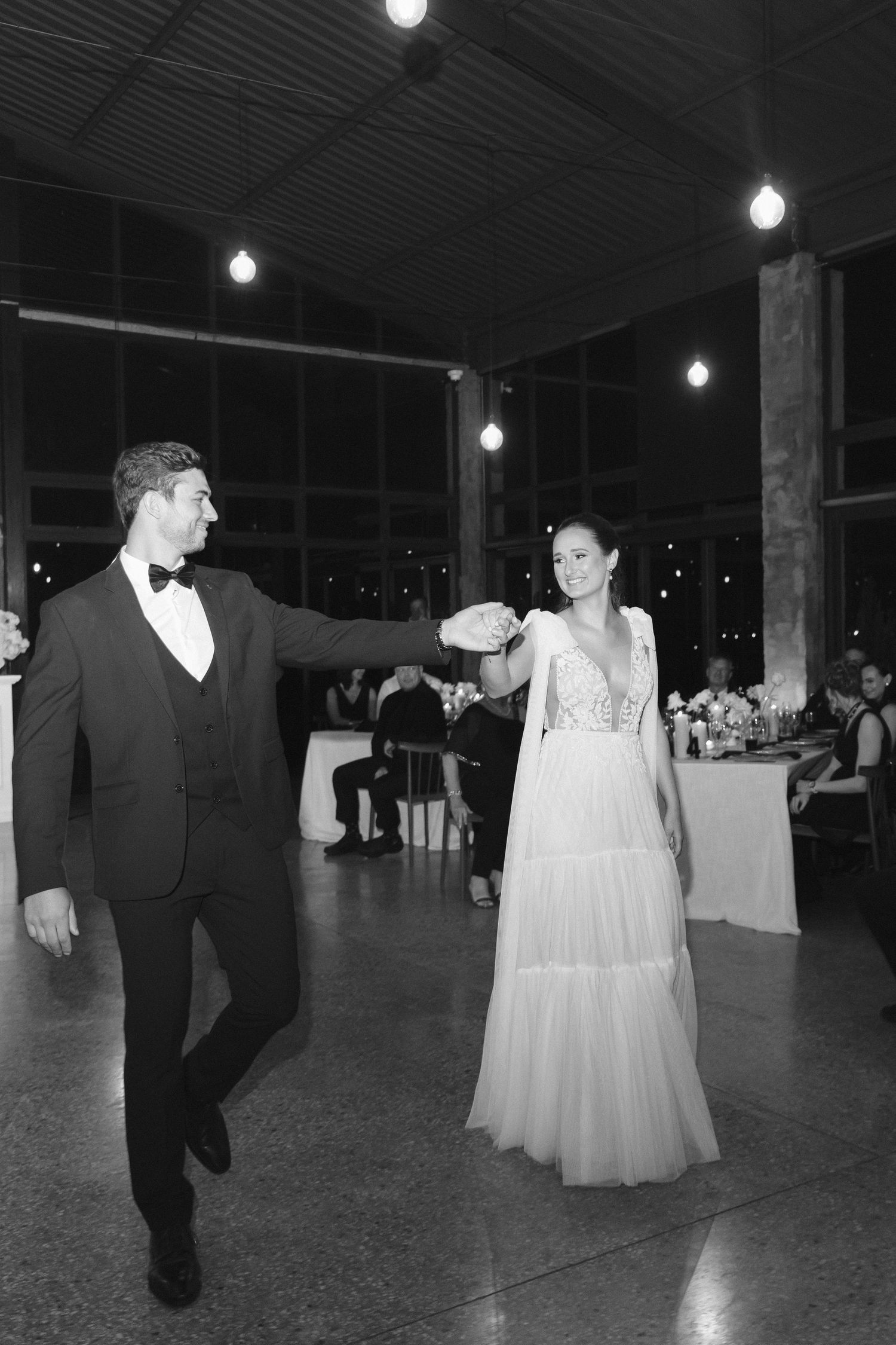 A sequence of black and white photos showing a couple dancing together at a wedding reception under hanging lights.