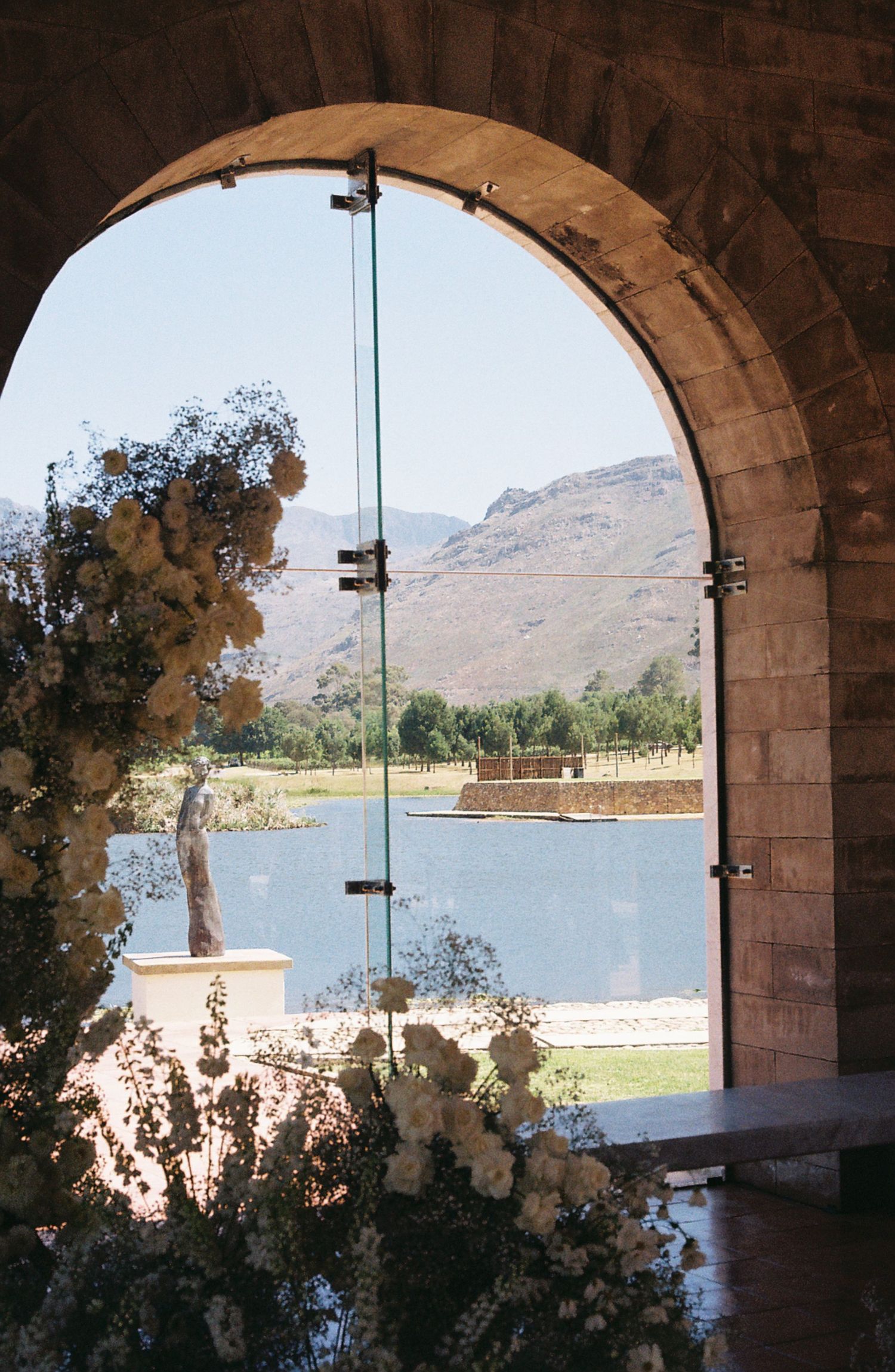 Stone archways frame a scenic lake view with mountains in the background.