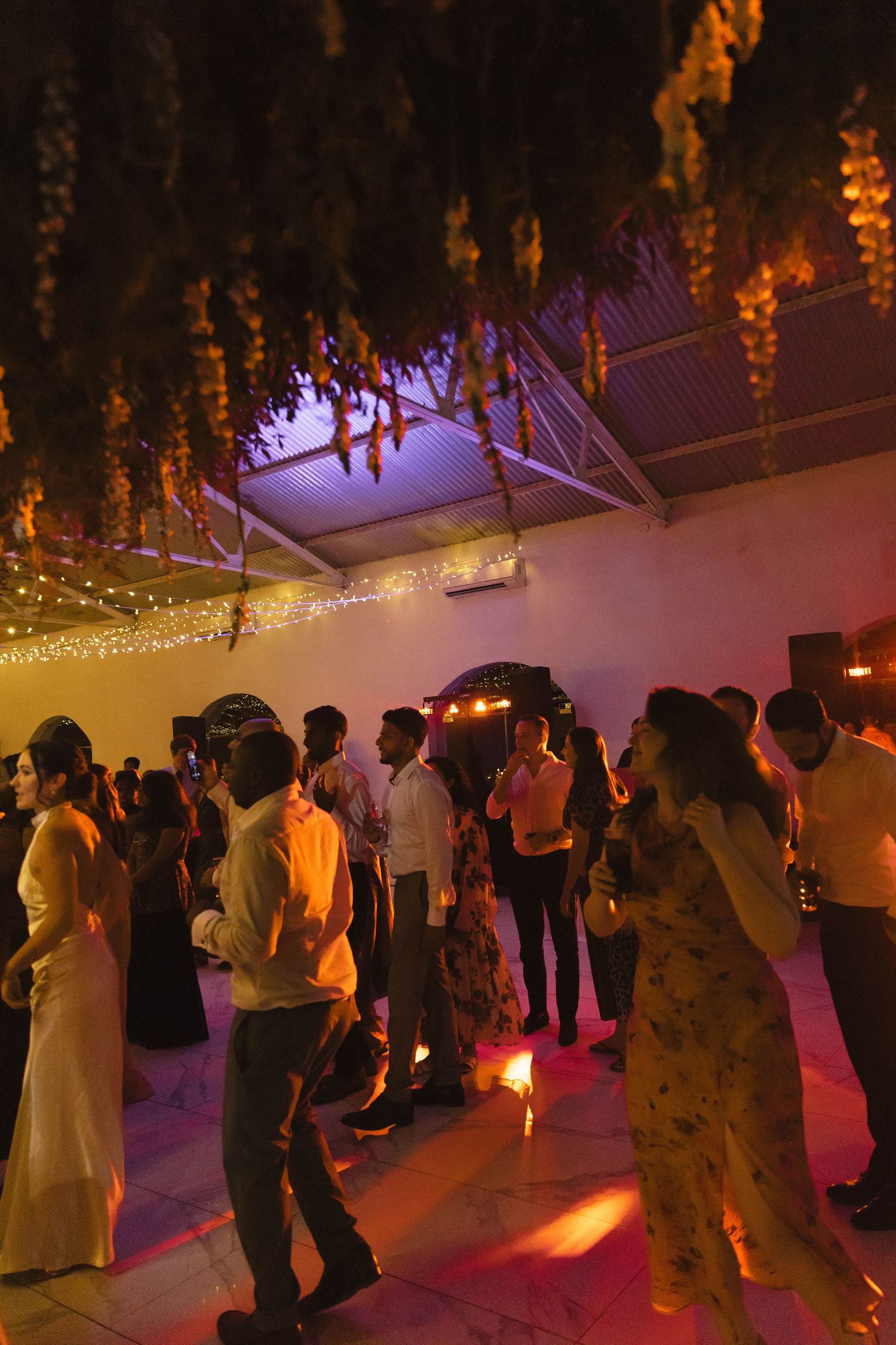 Wedding reception dance floor illuminated with warm lighting and hanging decorations.
