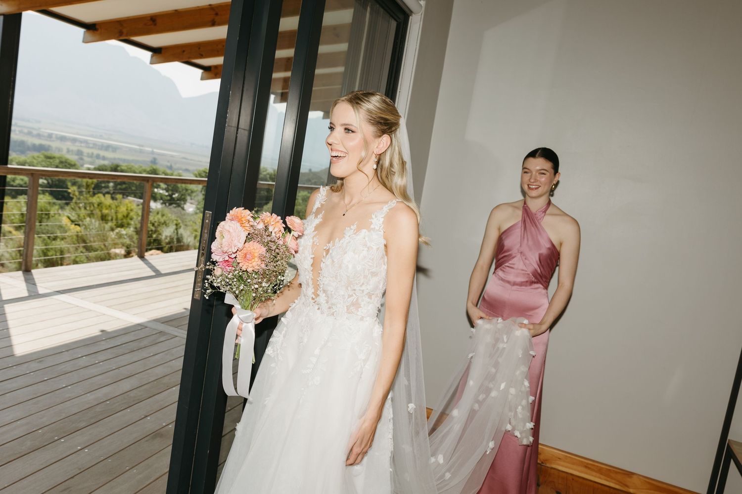 Wedding preparations in a bright modern room with glass doors and wooden beams.