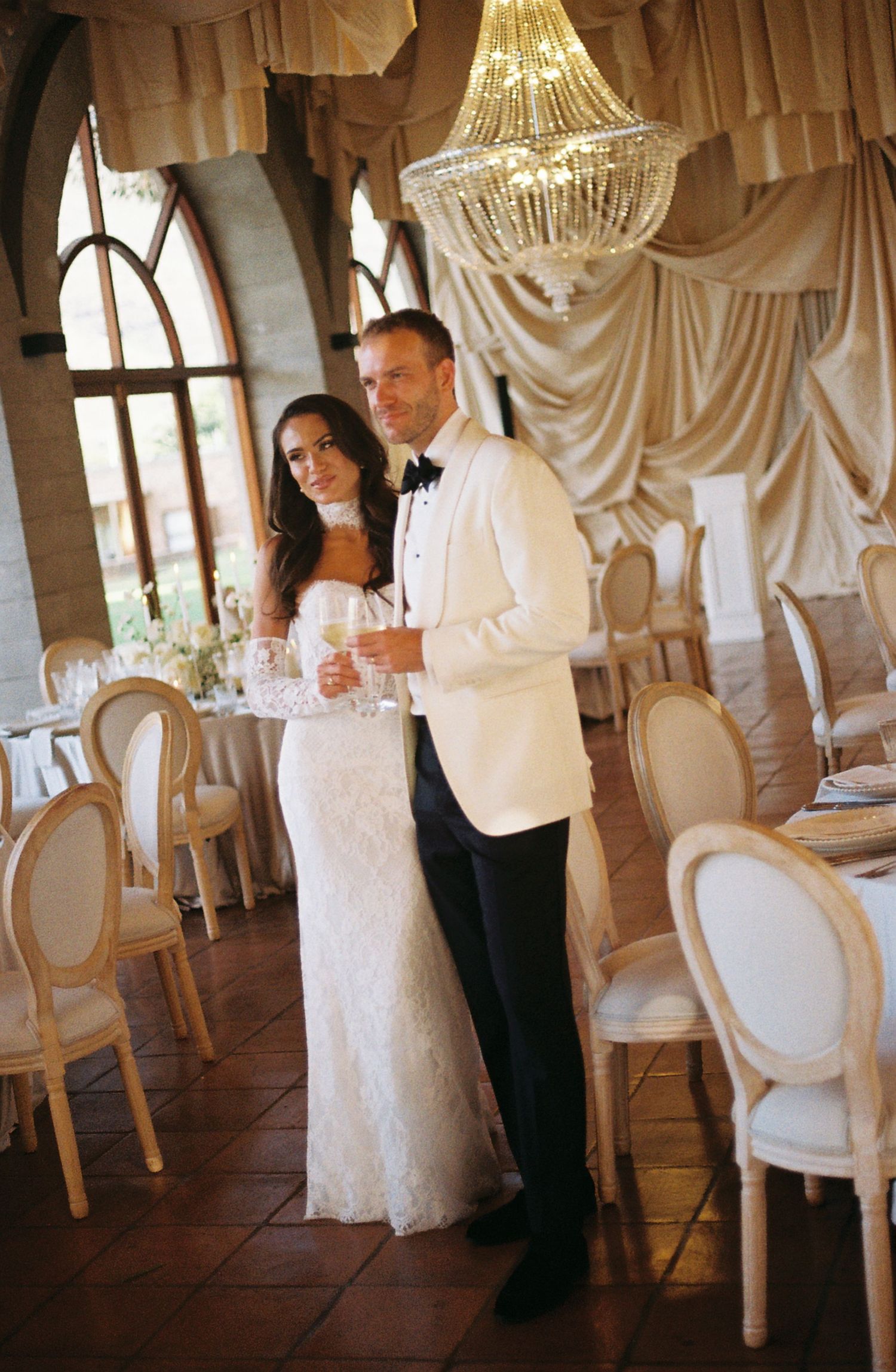 Elegant wedding reception venue with crystal chandelier and draped fabric decorations.