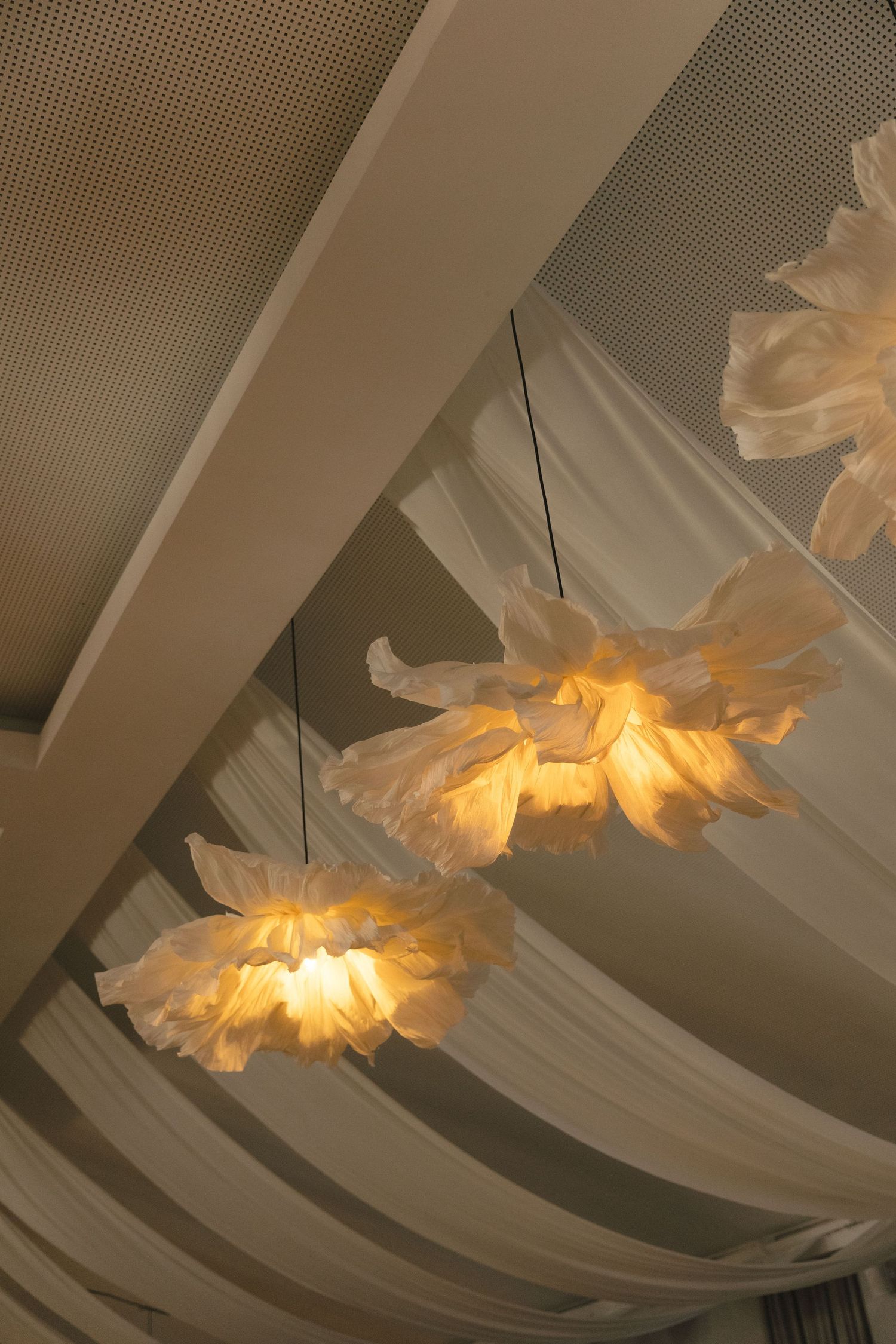 Elegant white fabric draping creates a romantic ceiling installation with warm glowing lights.