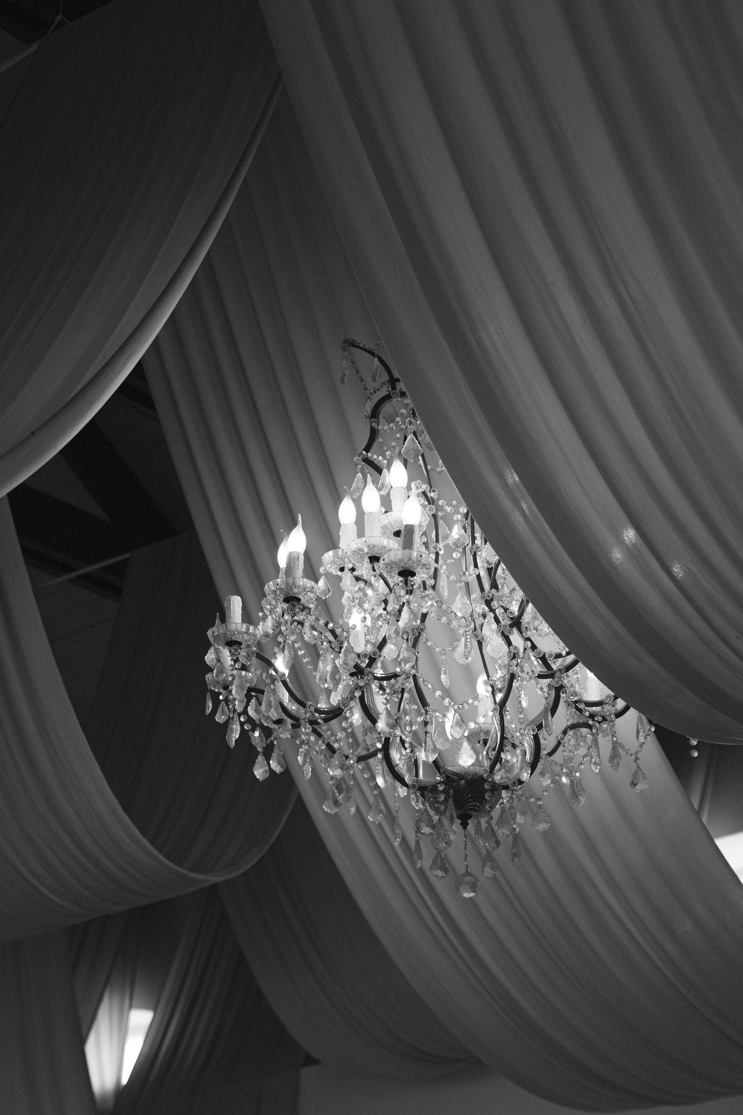 A sequence of black and white photos showing an ornate crystal chandelier hanging from draped fabric ceiling panels.