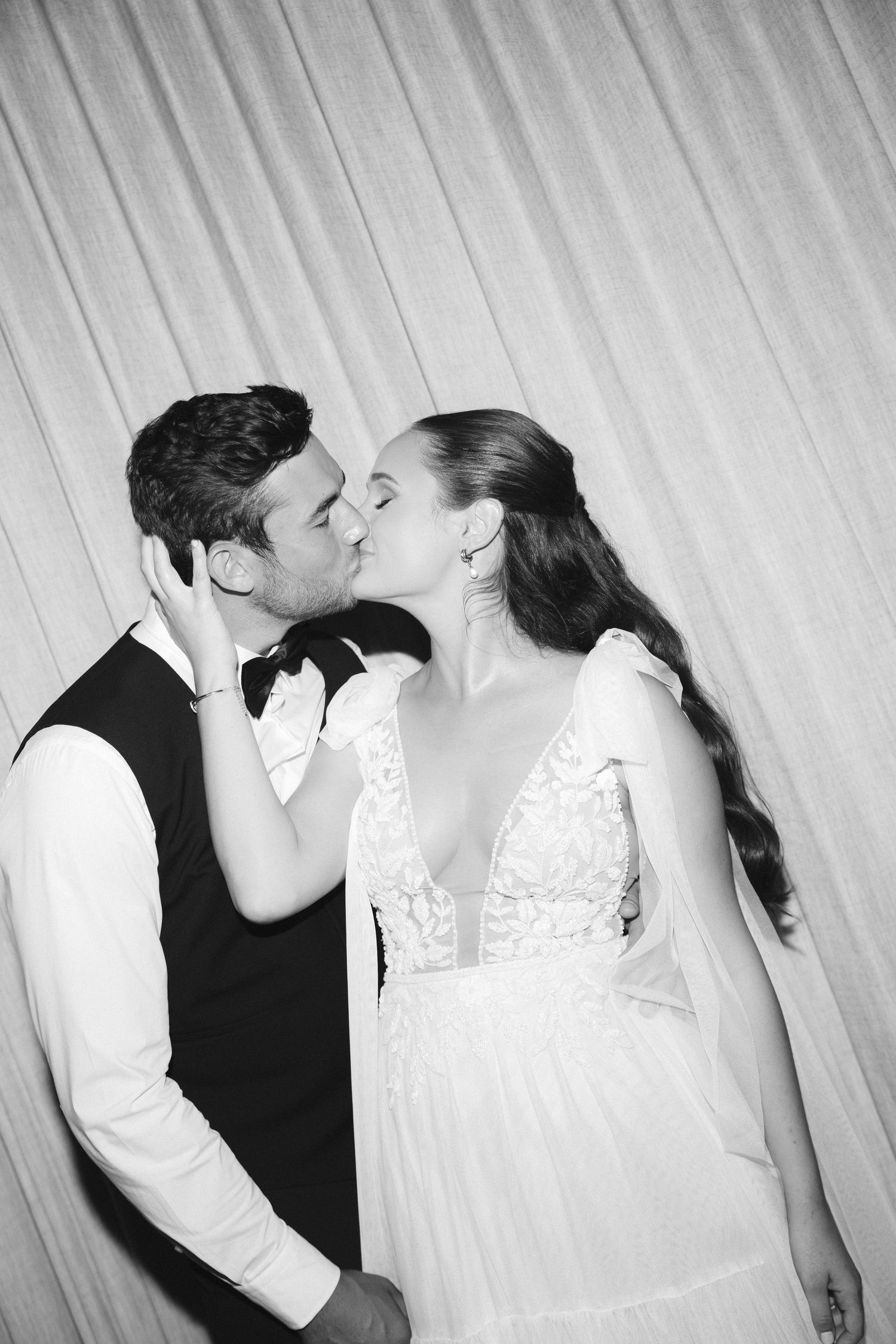 A series of four black and white photos showing a romantic kiss sequence between a couple in wedding attire.
