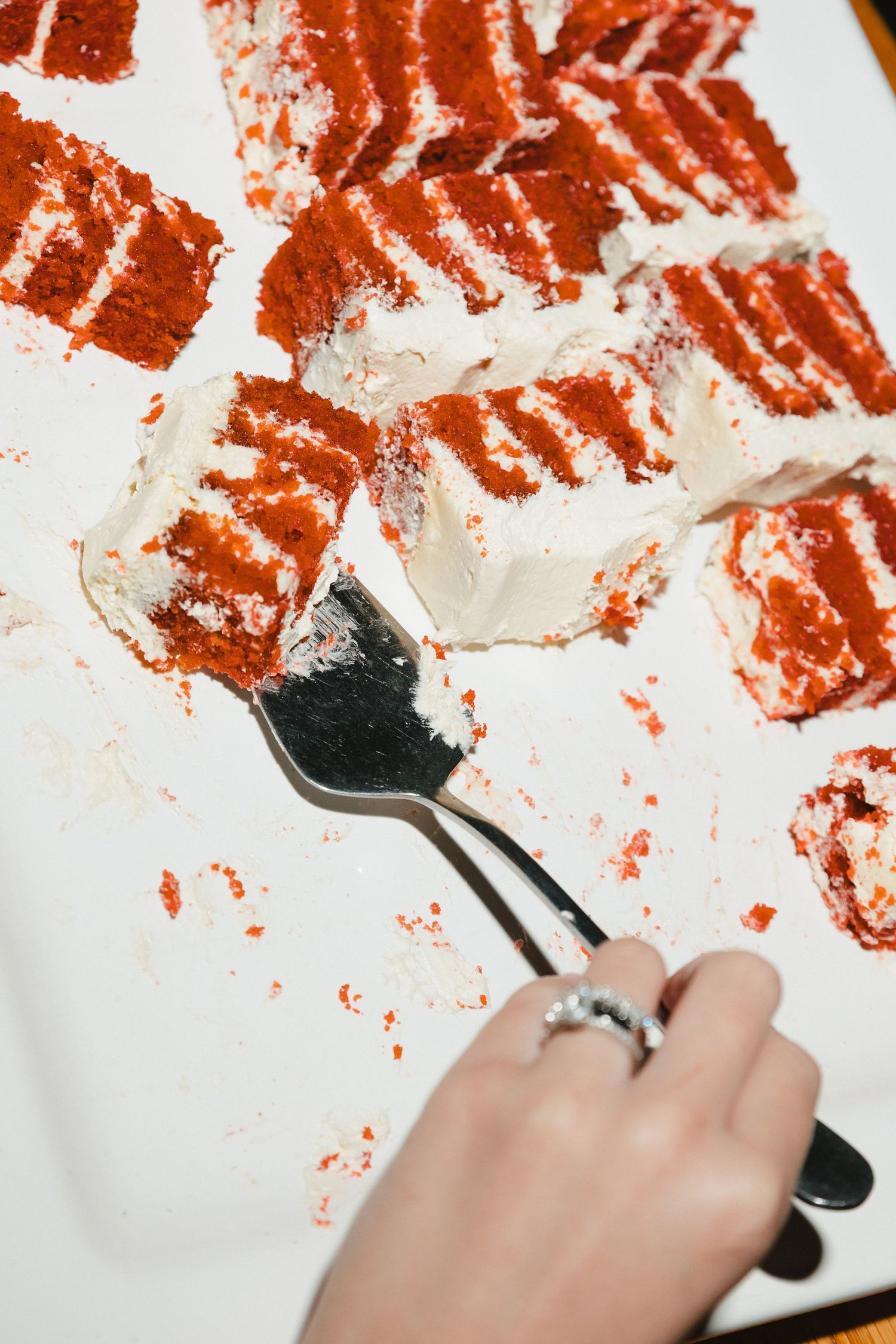 Someone using a fork to create red paint splatters and abstract patterns on white paper in an artistic process.