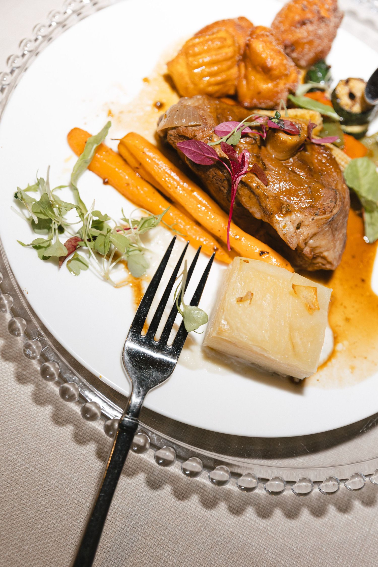 Series of elegant plated dishes with roasted vegetables and meat on decorative white plates.