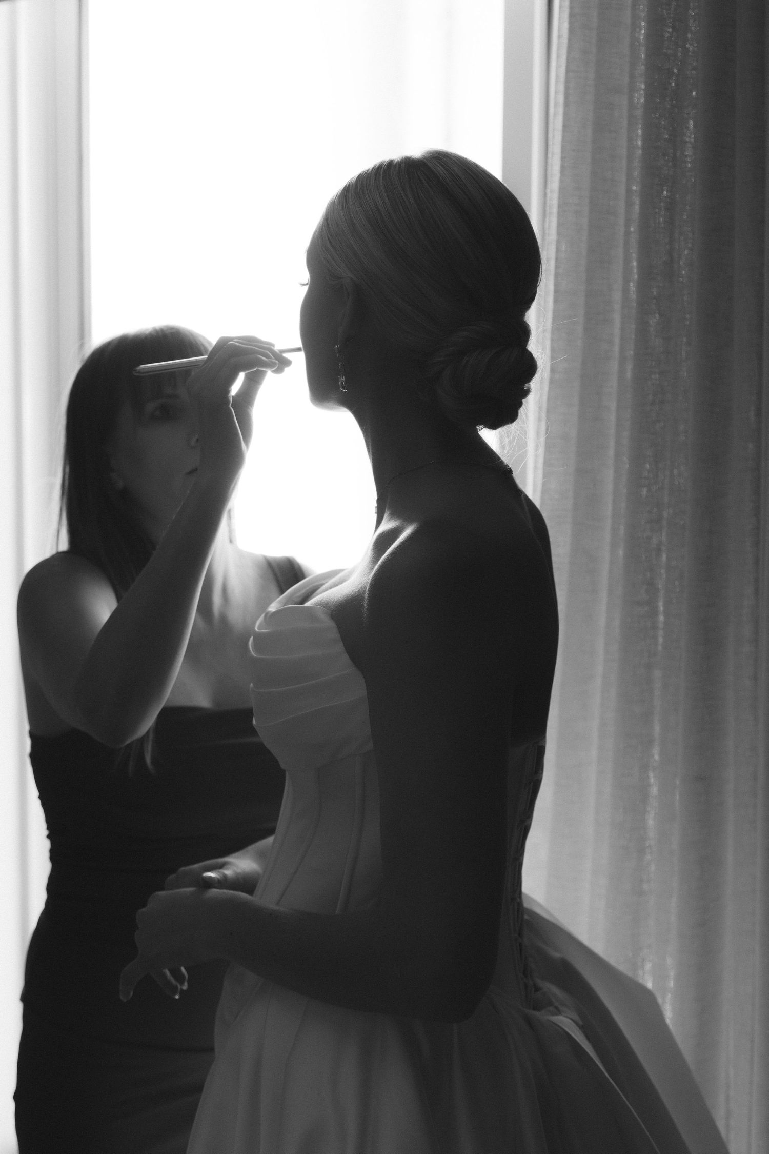 Silhouettes of people standing against bright window light creating a dramatic backlit effect.