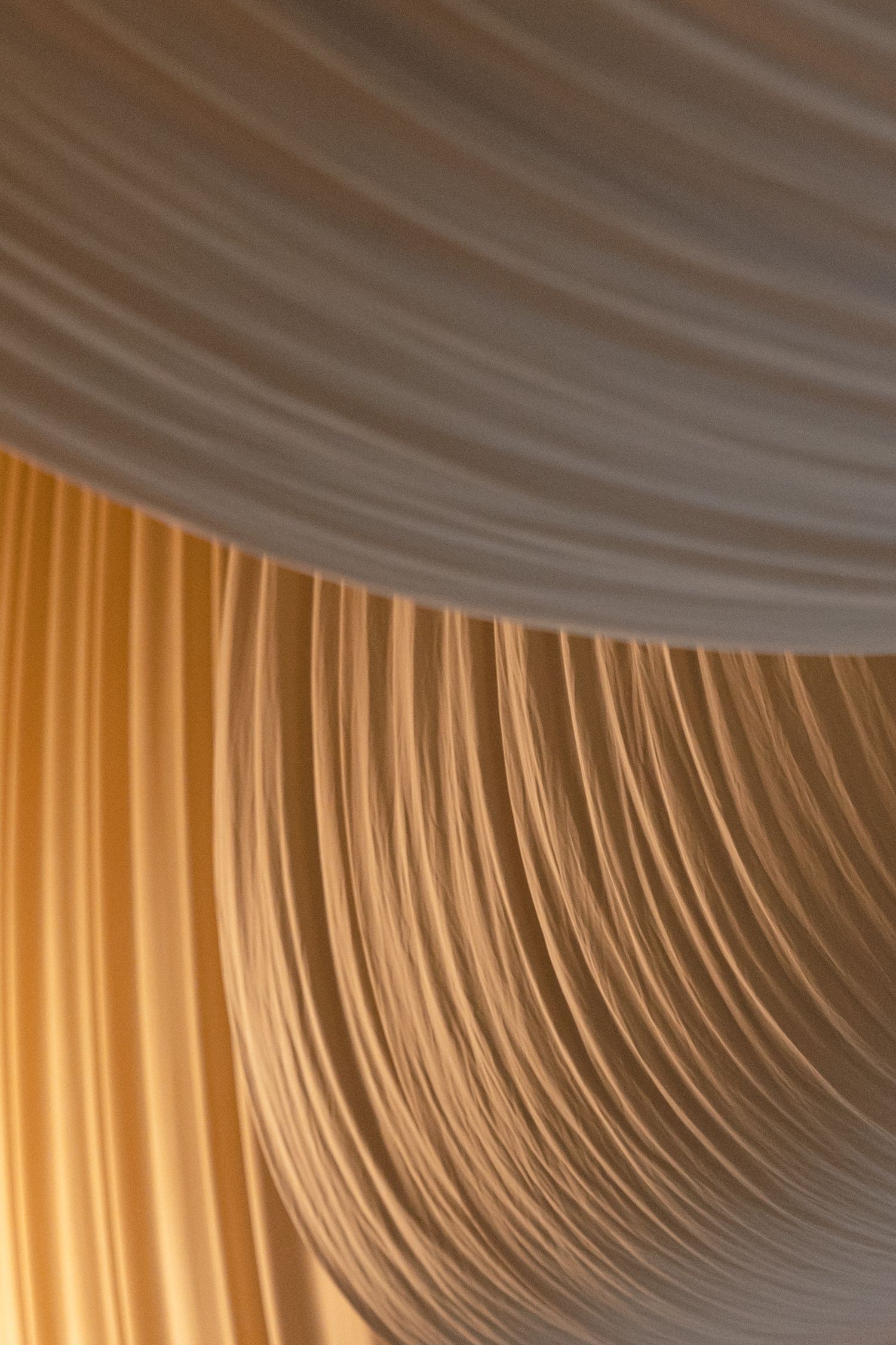 Elegant white and gold draped fabric creates flowing curves and soft folds in an abstract pattern.