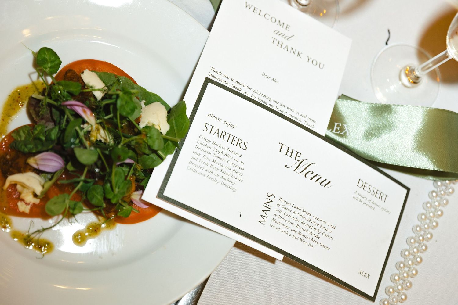 An elegant table setting with white place cards, menu cards, and fresh greenery decorations at a formal event.