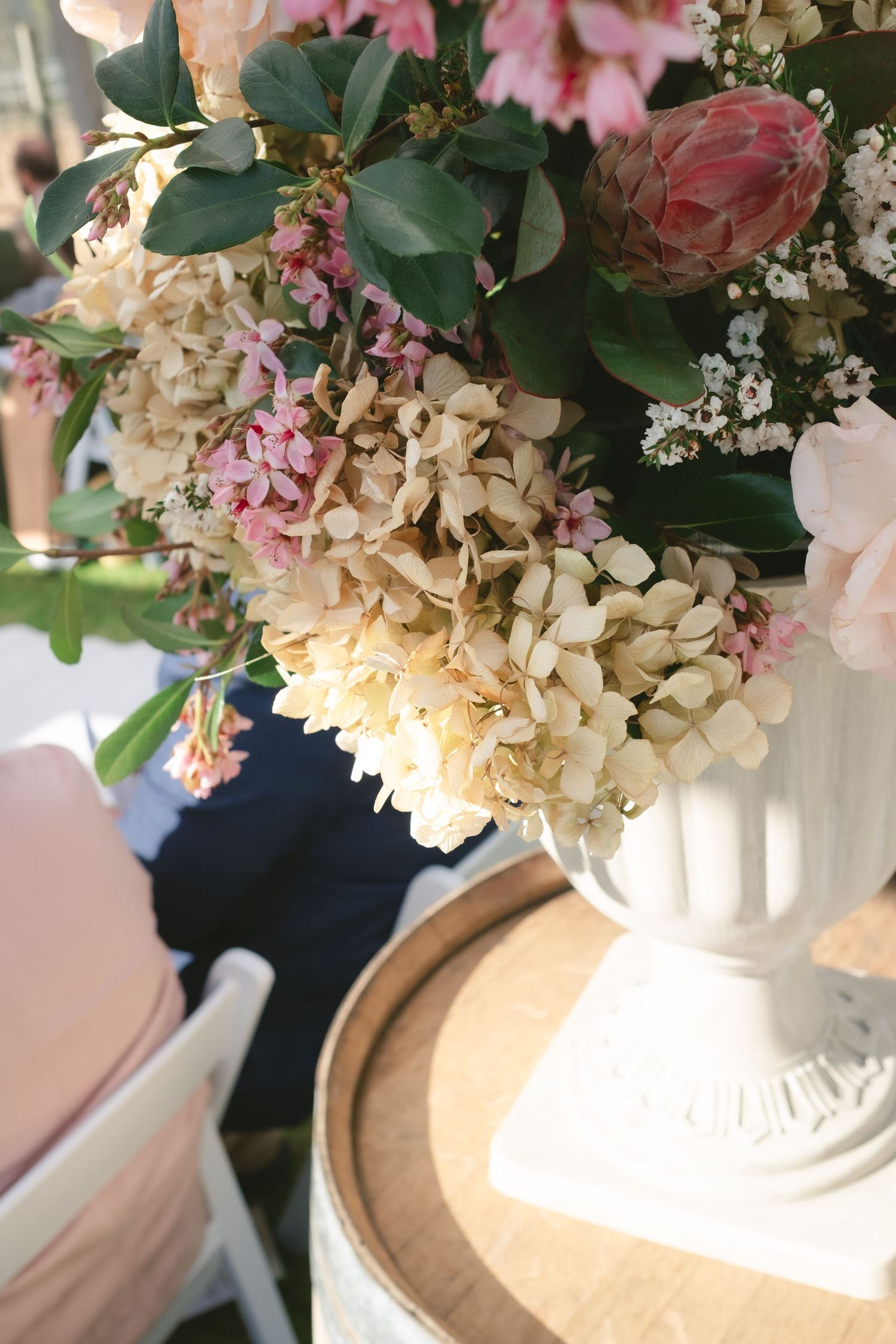 Elegant floral arrangement with hydrangeas and greenery in white vases displayed on a light surface.