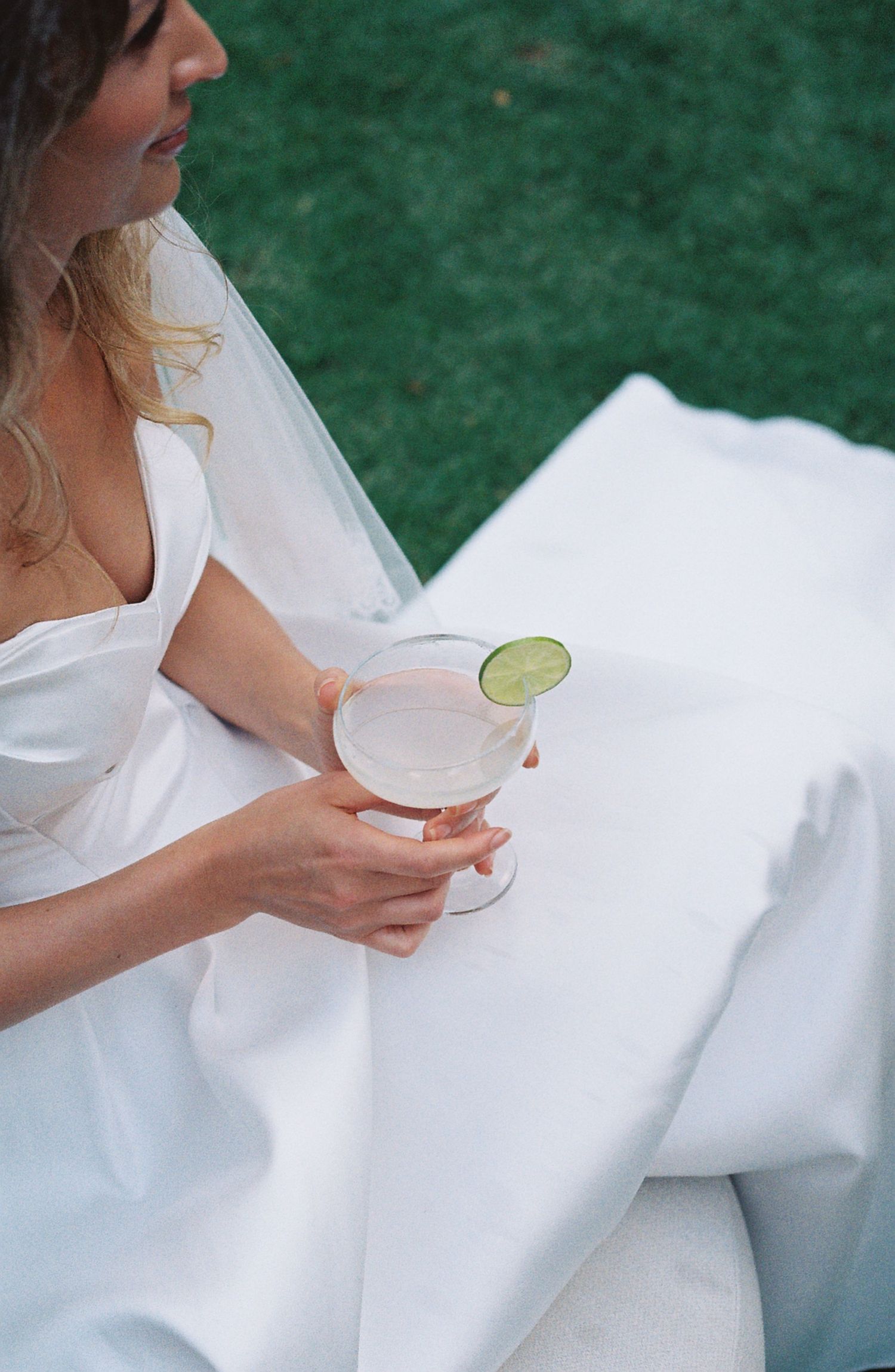 A series of photos showing hands holding a cocktail glass with a lime garnish against a white dress and green background.