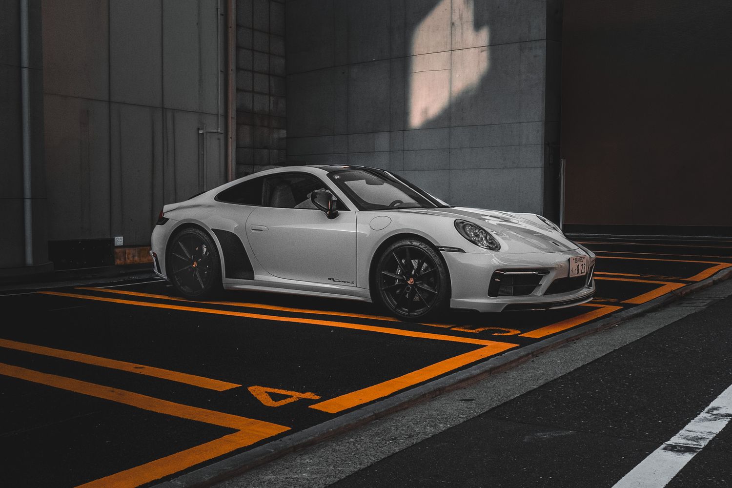 White Porsche 911 GT3 parked in a modern garage with orange line markings on dark flooring.