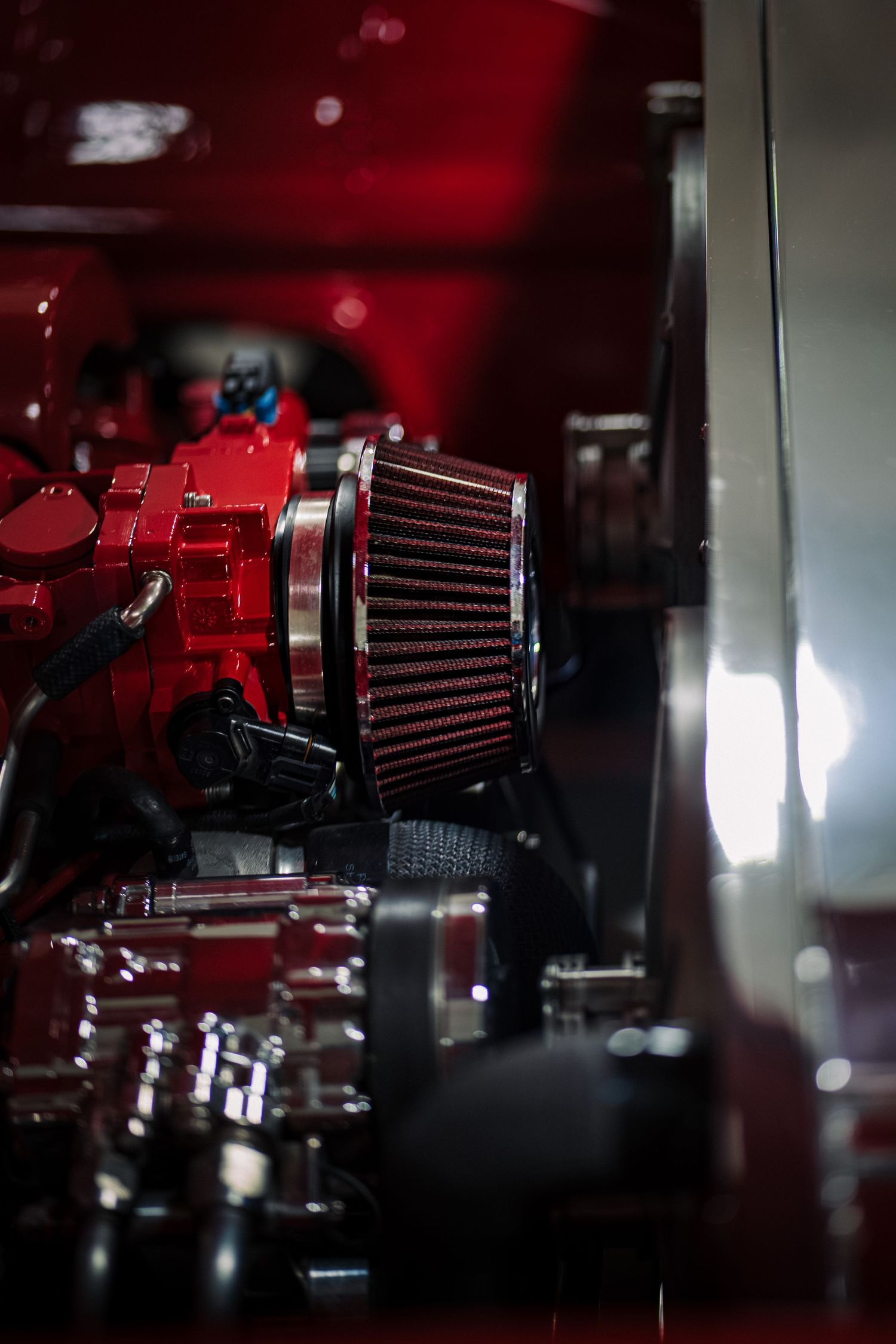 Red performance air filters and engine components shown in dramatic low-key lighting.