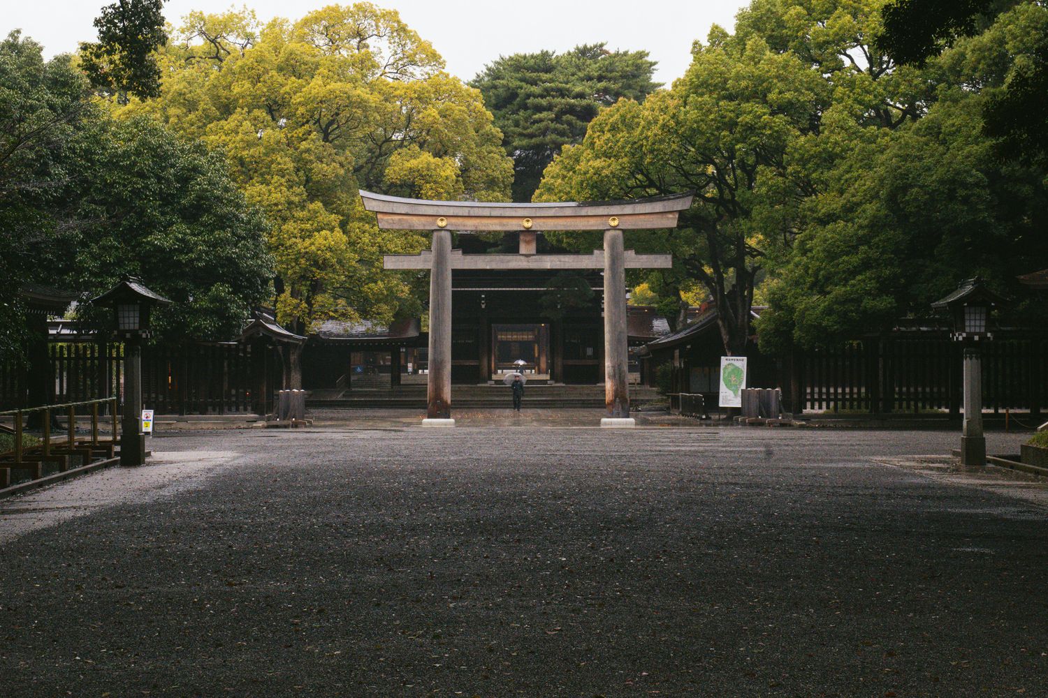 Stone torii gate entrance to a serene Japanese shrine surrounded by lush green trees.