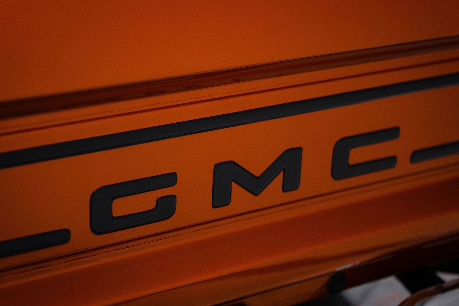 Orange painted vehicle body panel with GMC lettering visible.