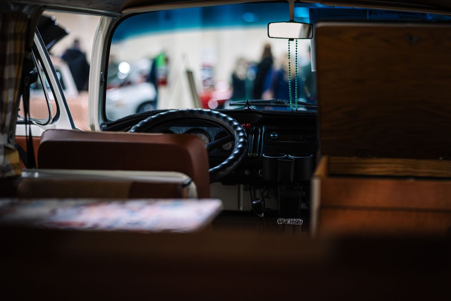 Interior view of vintage car dashboard and brown leather seats shot through rear window with shallow depth of field.