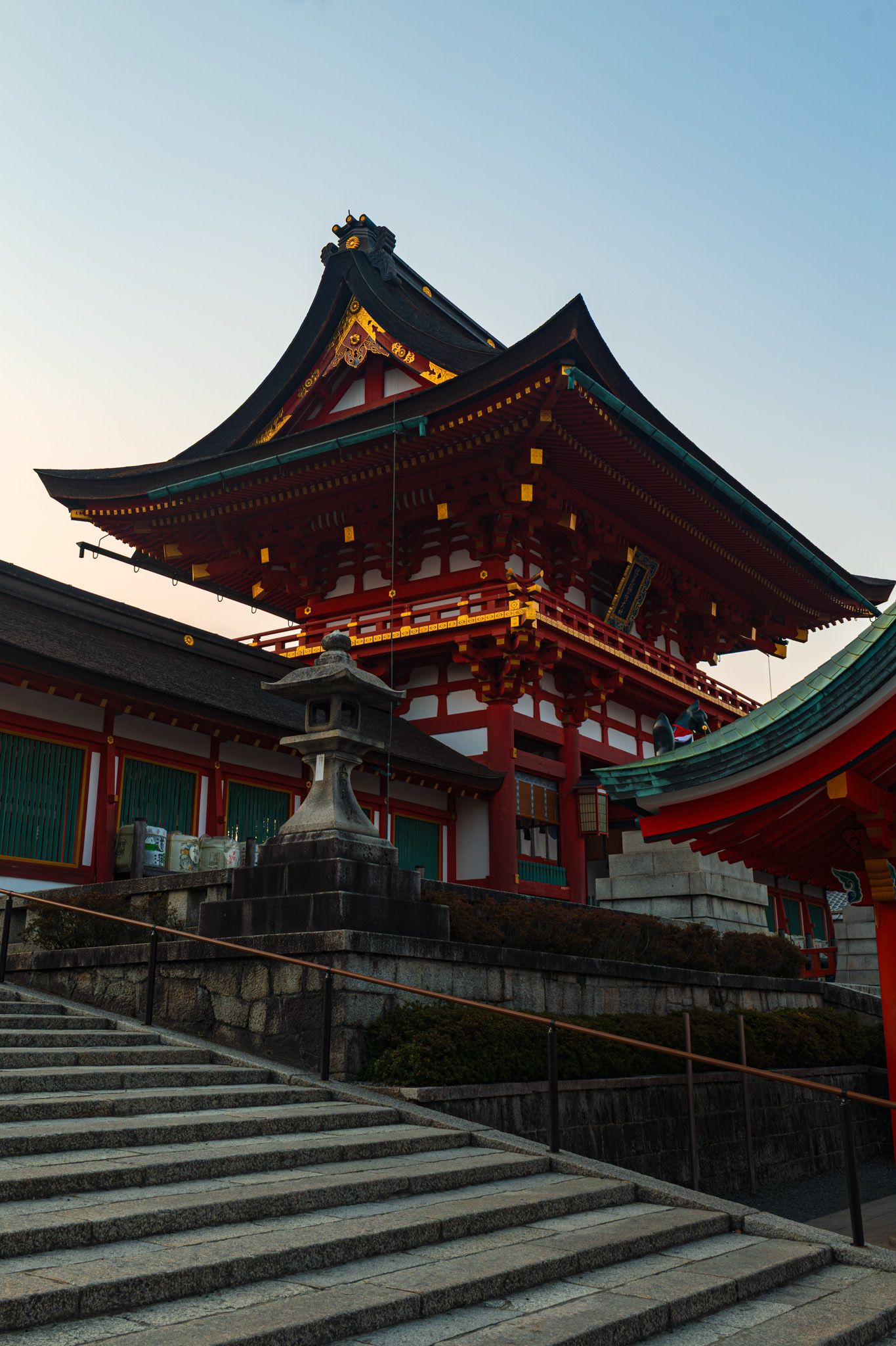 Red Japanese Shinto shrine with traditional pagoda architecture and stone steps at dusk, Fushimi Inari, Kyoto.