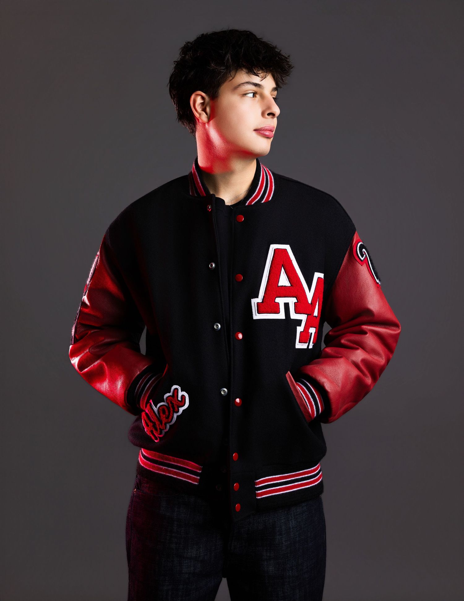 Young man wearing a black and red varsity letterman jacket with AL letters in a studio setting.
