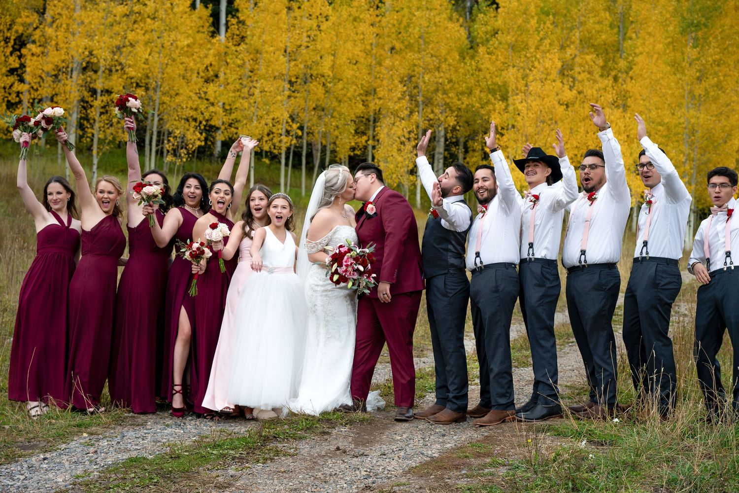 Wedding party celebrates in burgundy and white attire with autumn yellow aspen trees backdrop.