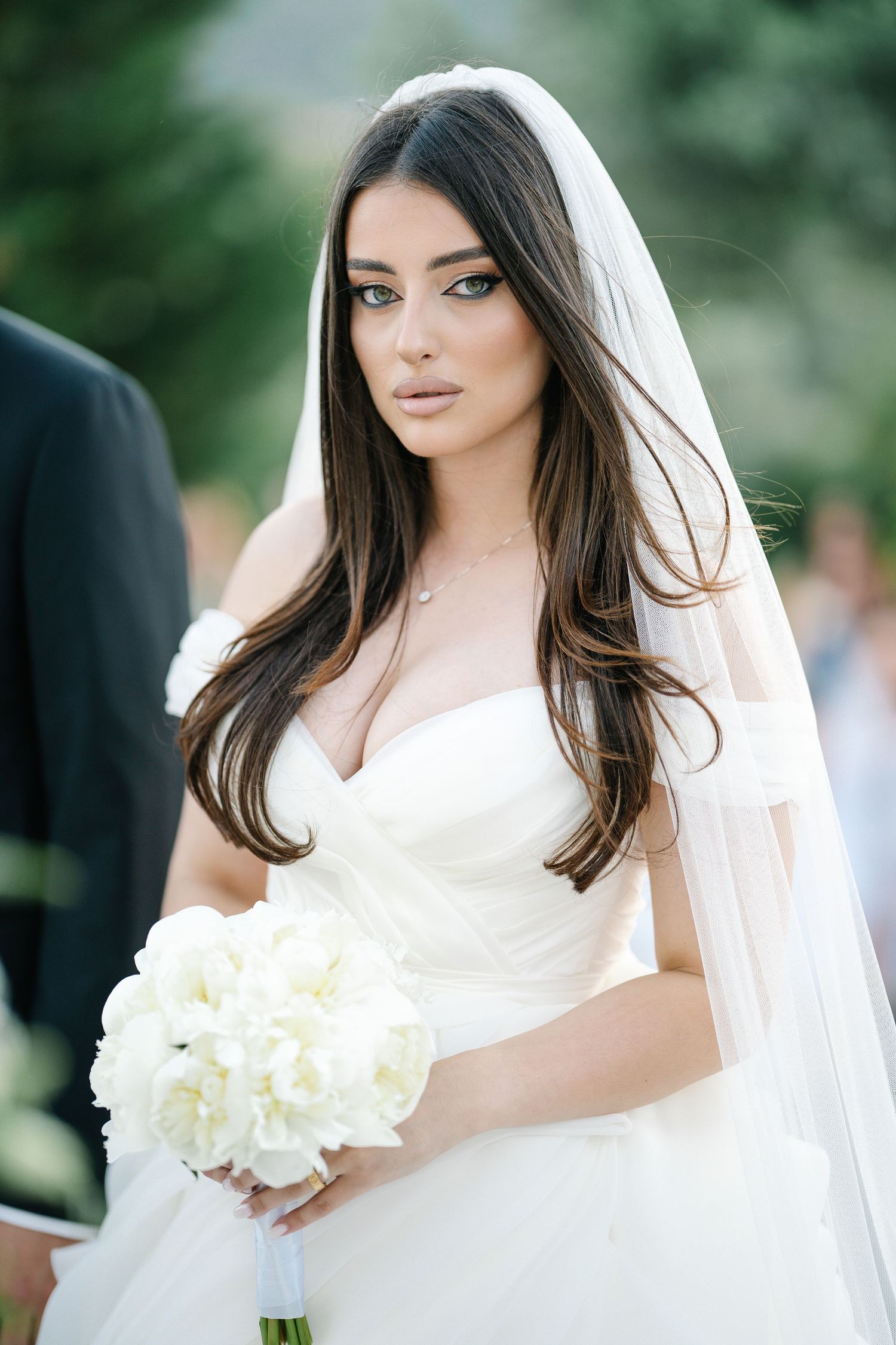 Elegant white wedding dress and veil with white peony bouquet.
