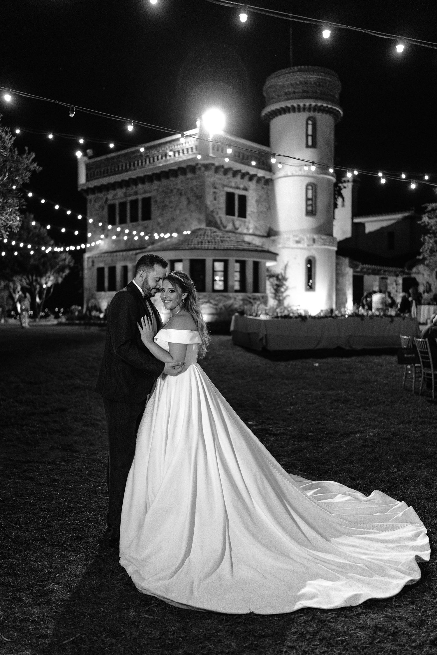 A romantic nighttime wedding dance scene under string lights with a flowing white ballgown dress creating elegant silhouettes.